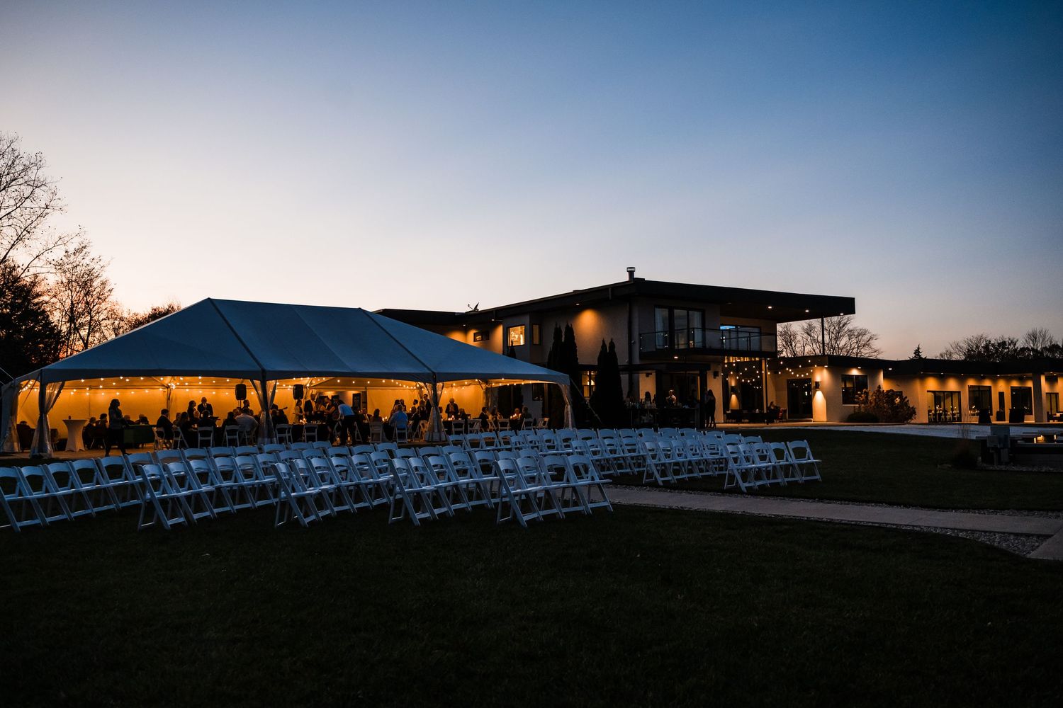 Panoramic sunset view of a wedding venue with white chairs set up outdoors.