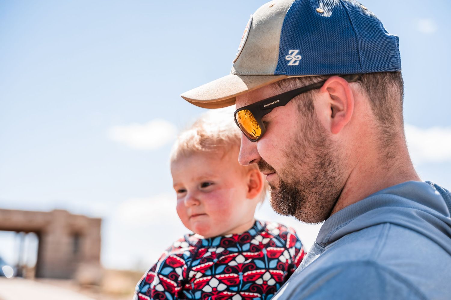 A sunny desert scene with matching baseball caps and sunglasses against blue sky.