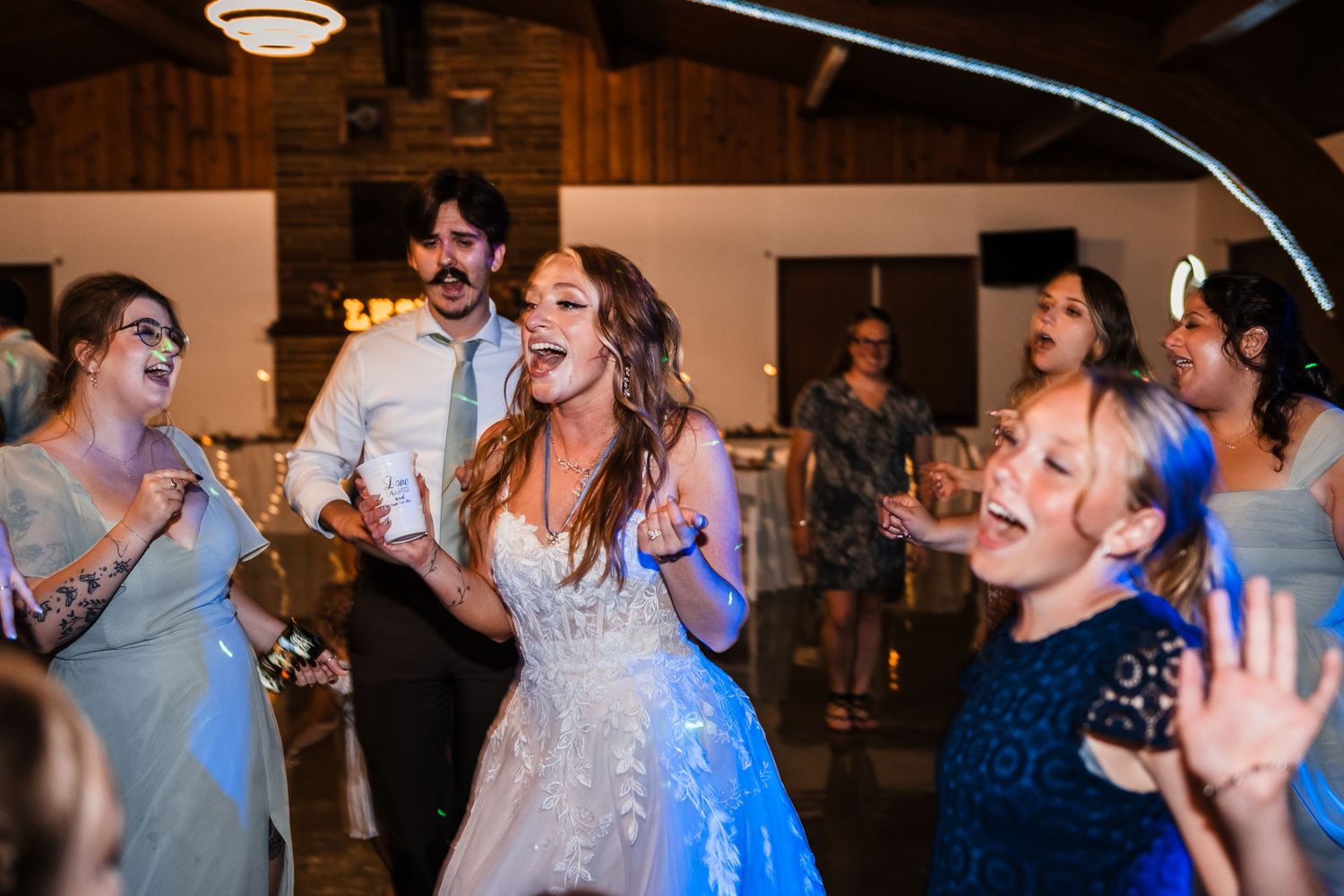 Wedding reception guests dancing and celebrating in a rustic barn venue.