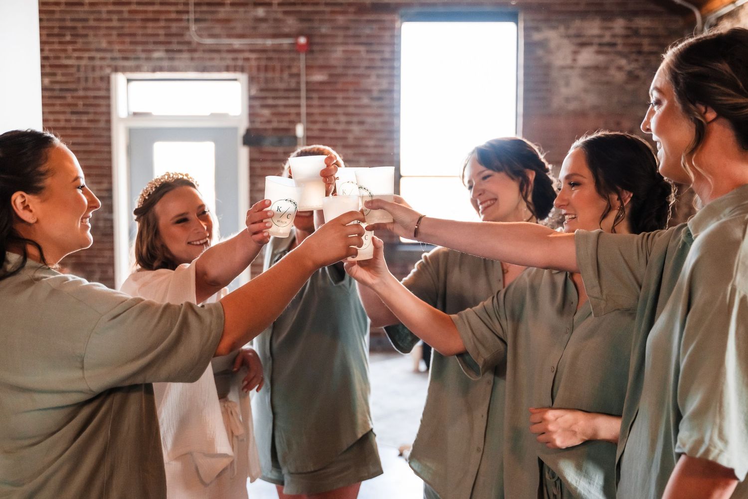 A group of team members in gray attire celebrate together by raising their hands for a celebratory high five moment.
