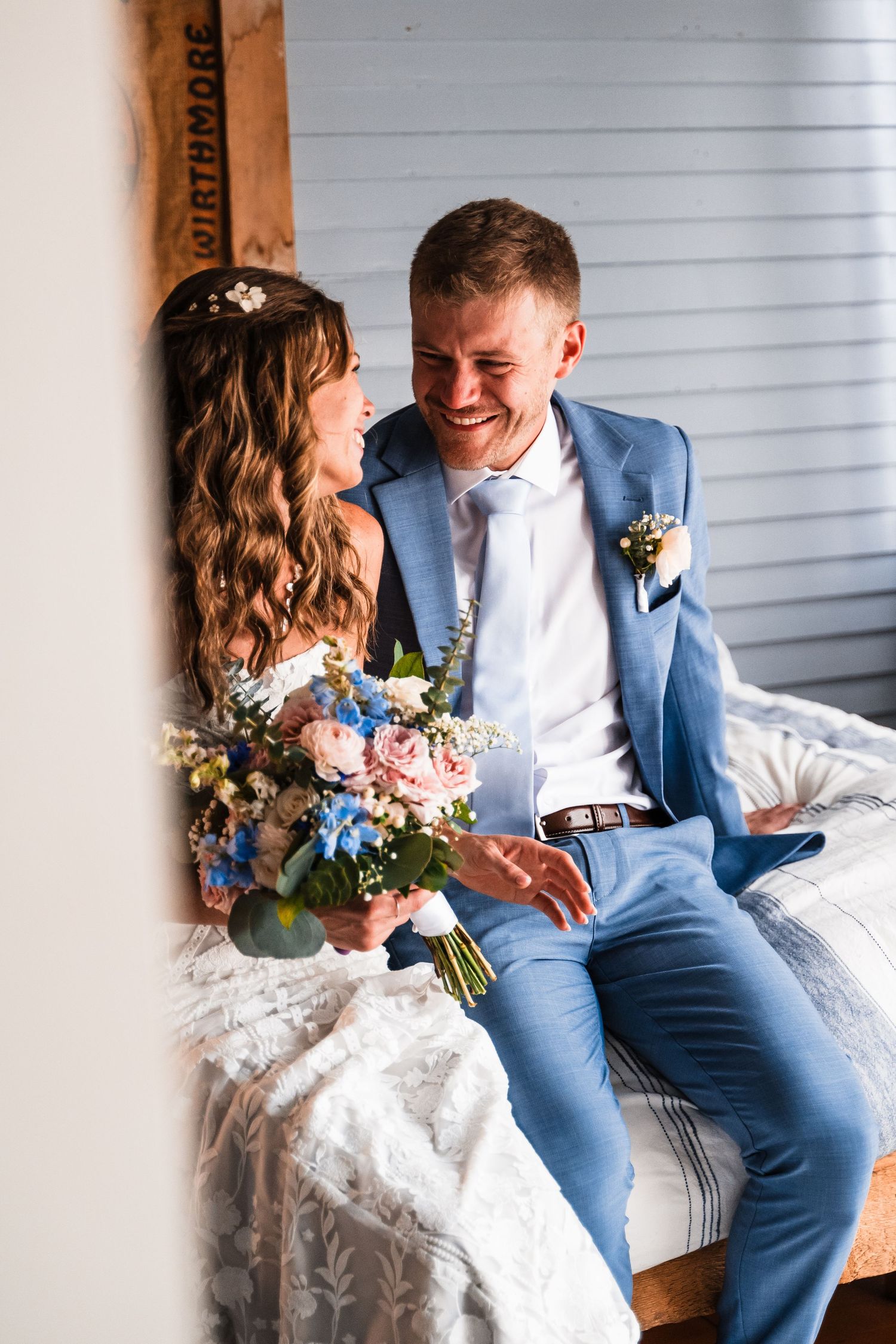 Couple sharing joyful moment while sitting with colorful wedding bouquet.