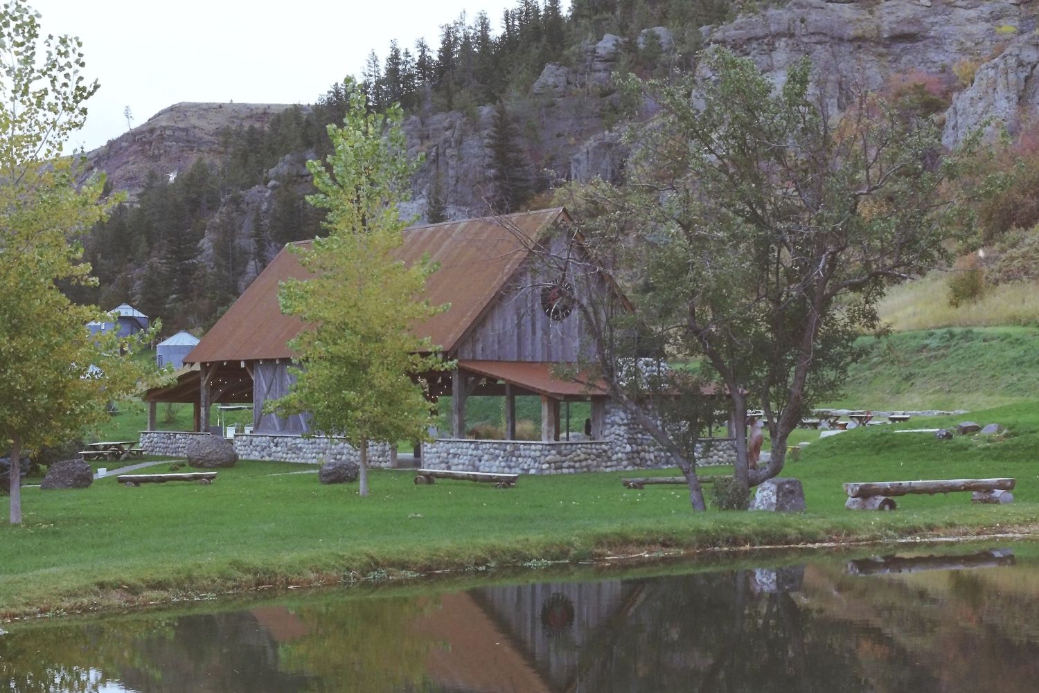 A scenic mountain landscape with rustic wooden cabins nestled among evergreen trees and rolling green hills.