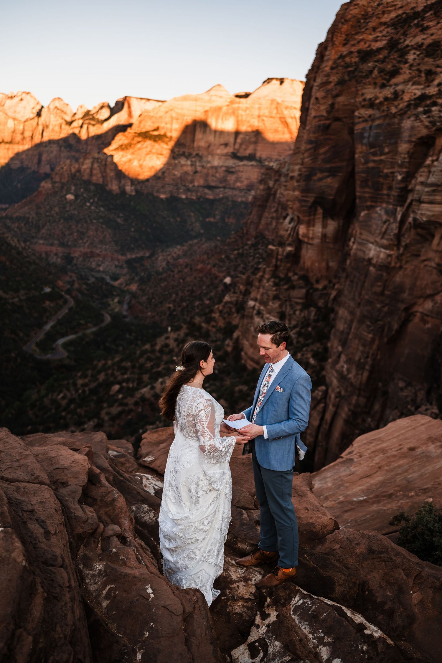 Bride and groom exchanging vows on rocky cliff at Zion National Park during sunset ceremony.