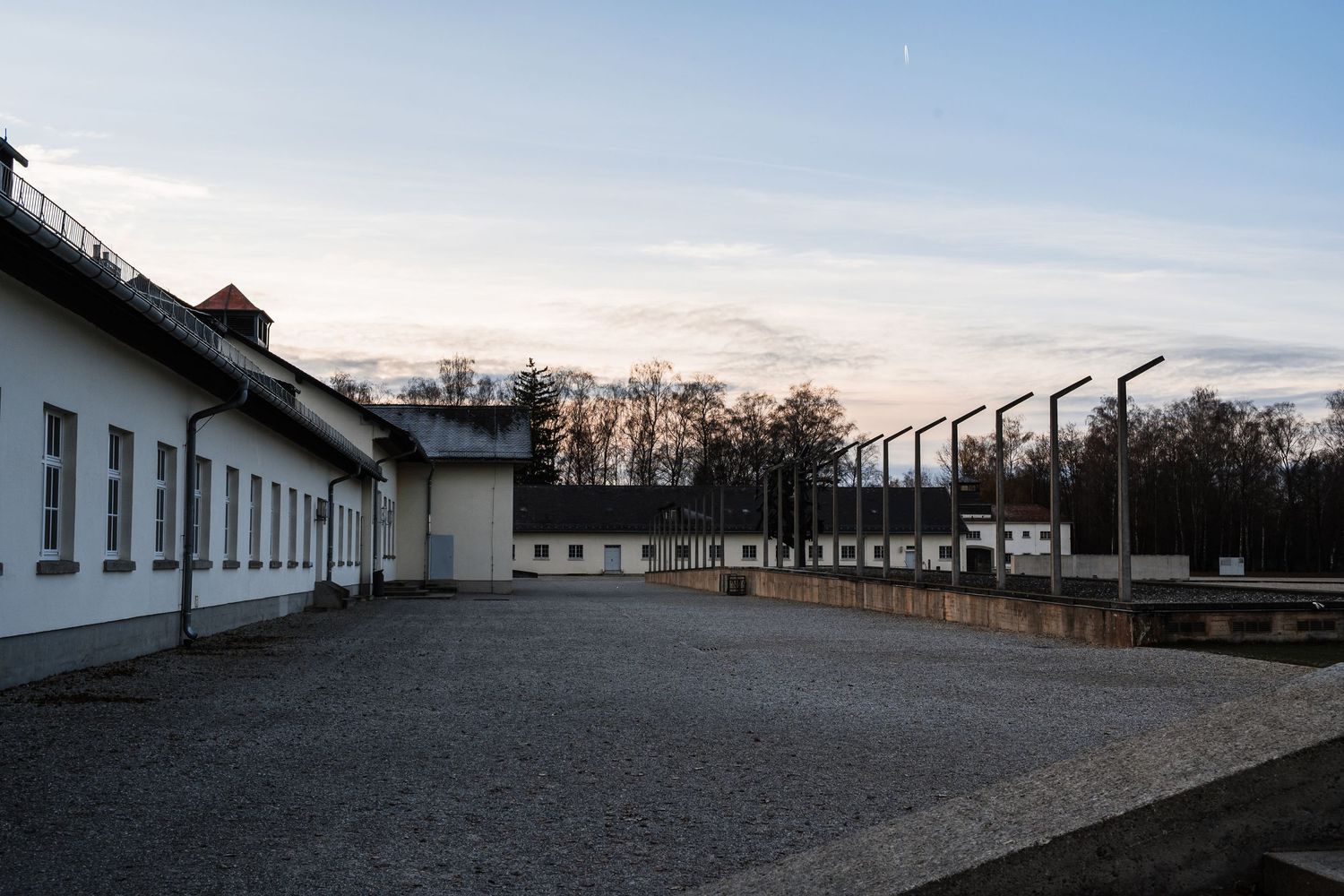 A panoramic view of the former Sachsenhausen concentration camp memorial site with barracks and guard towers at sunset.