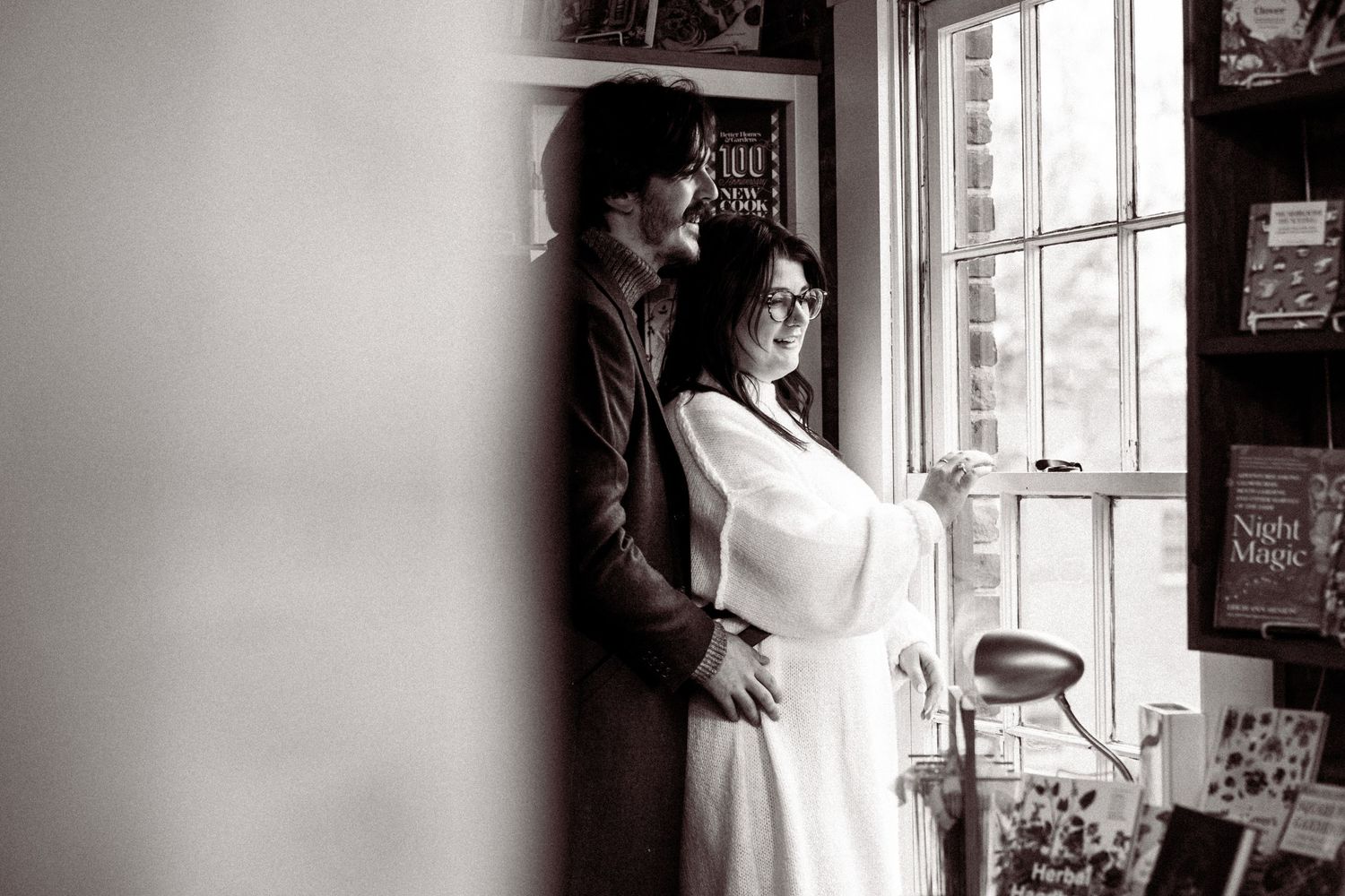 Artistic black and white portrait by a window with natural light streaming in.