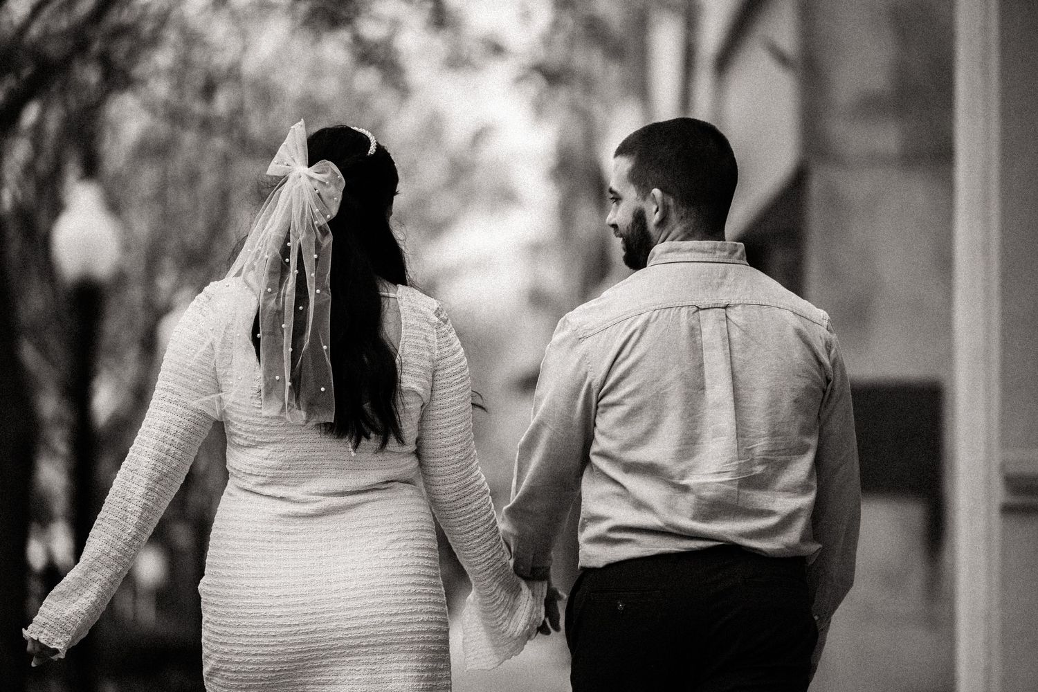 A romantic black and white photo of a couple walking together outdoors.