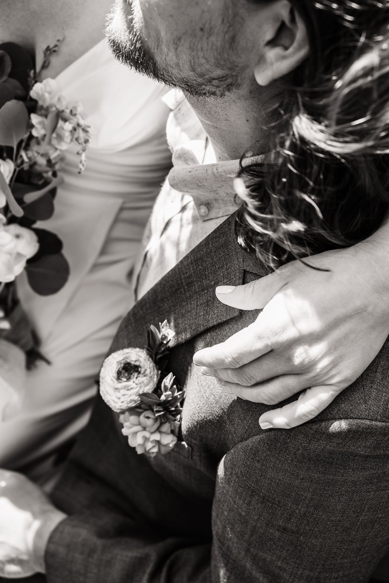Close-up black and white shot of wedding attire details including boutonniere and formal wear.