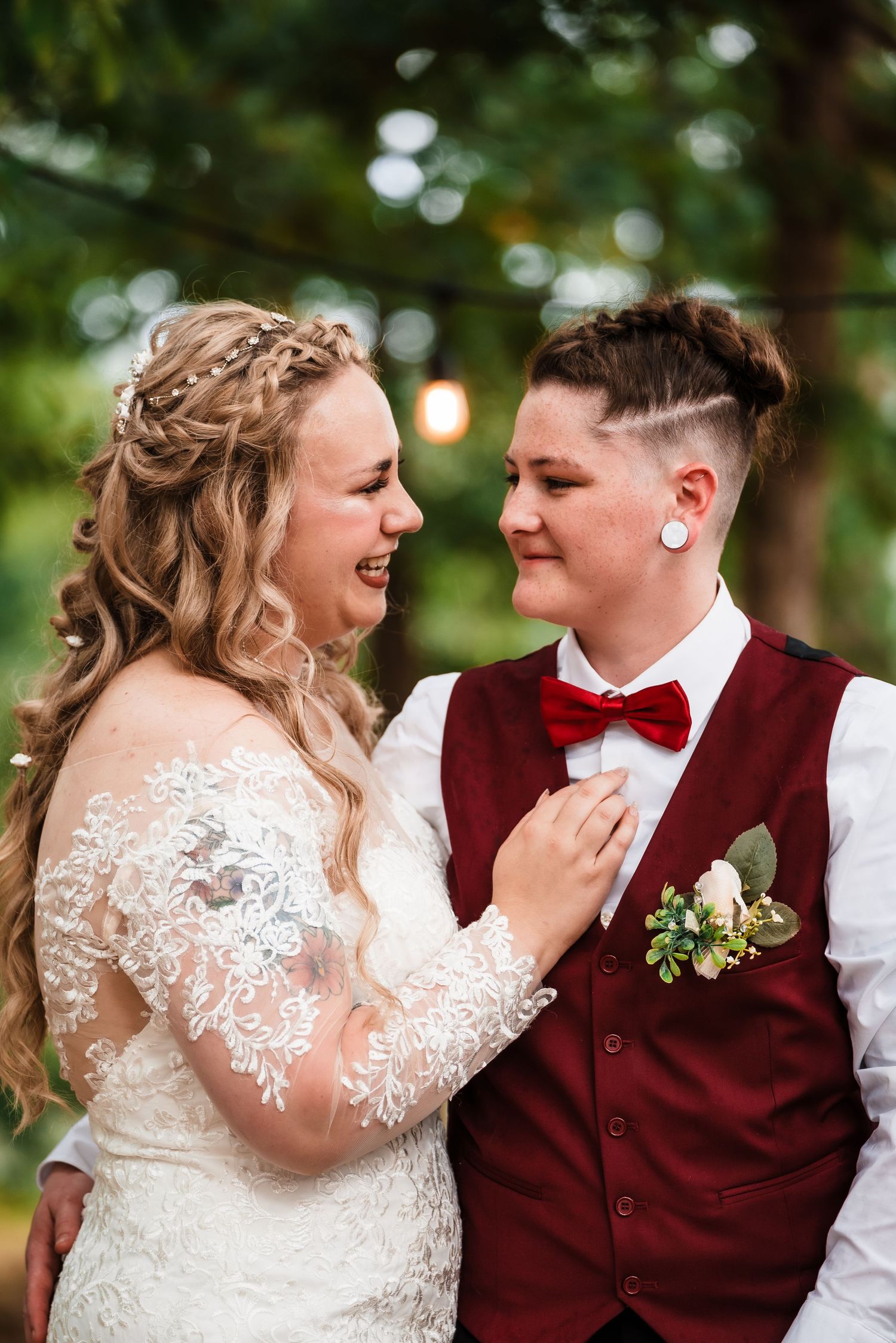 Couple in wedding attire share intimate moment outdoors with natural lighting.
