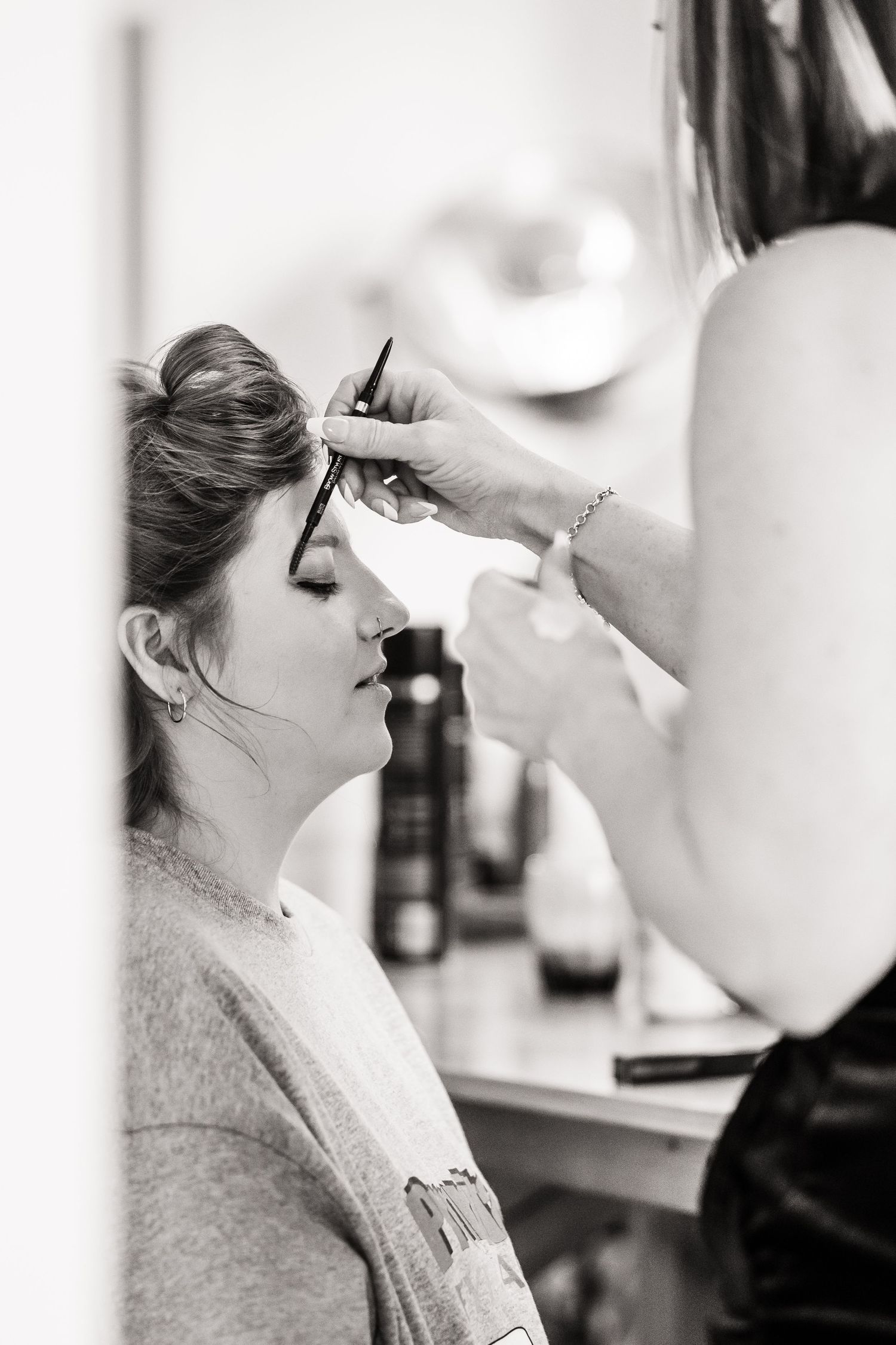 Close-up of wedding day makeup application in black and white.