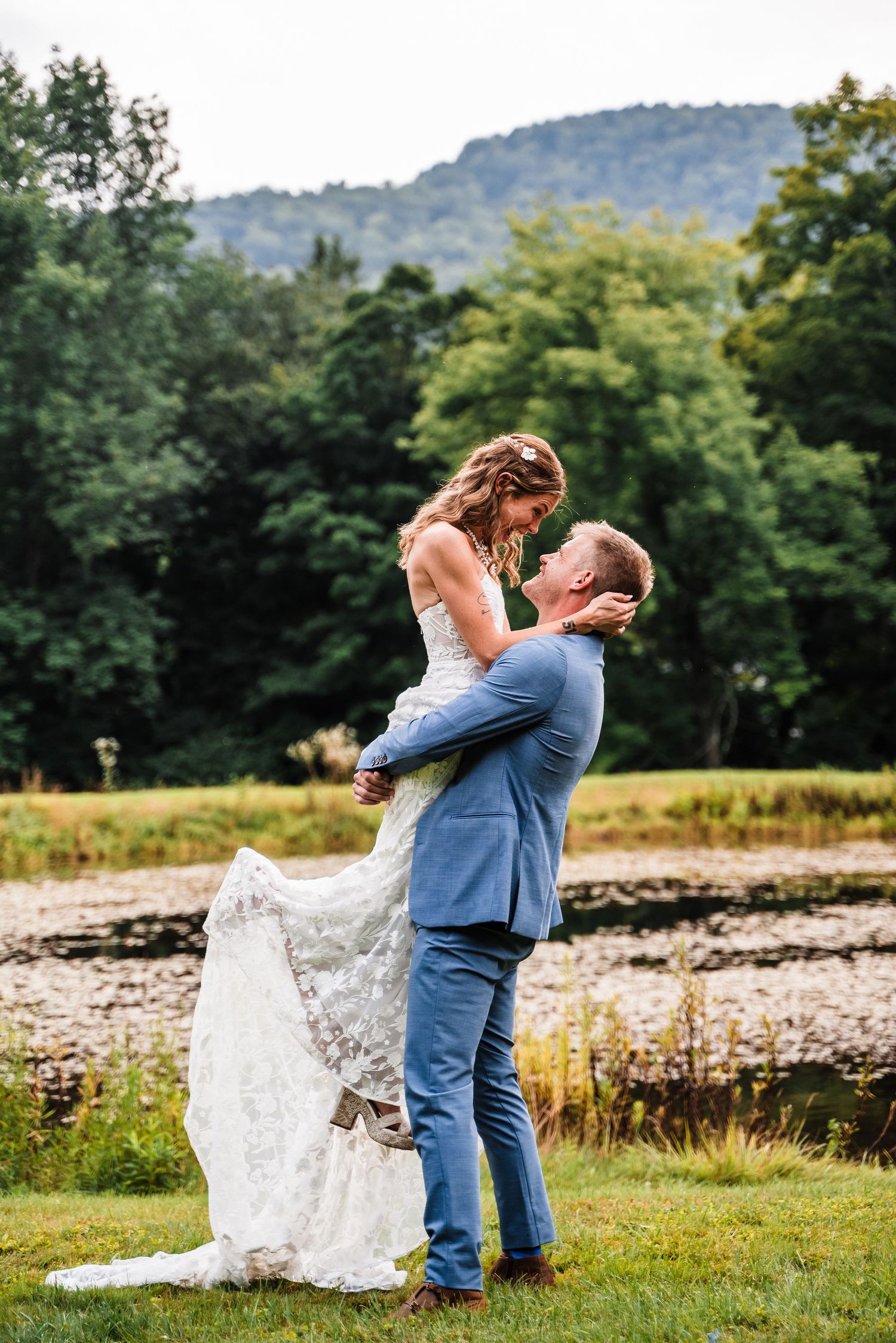 A joyful wedding lift pose captured against mountains and natural scenery.