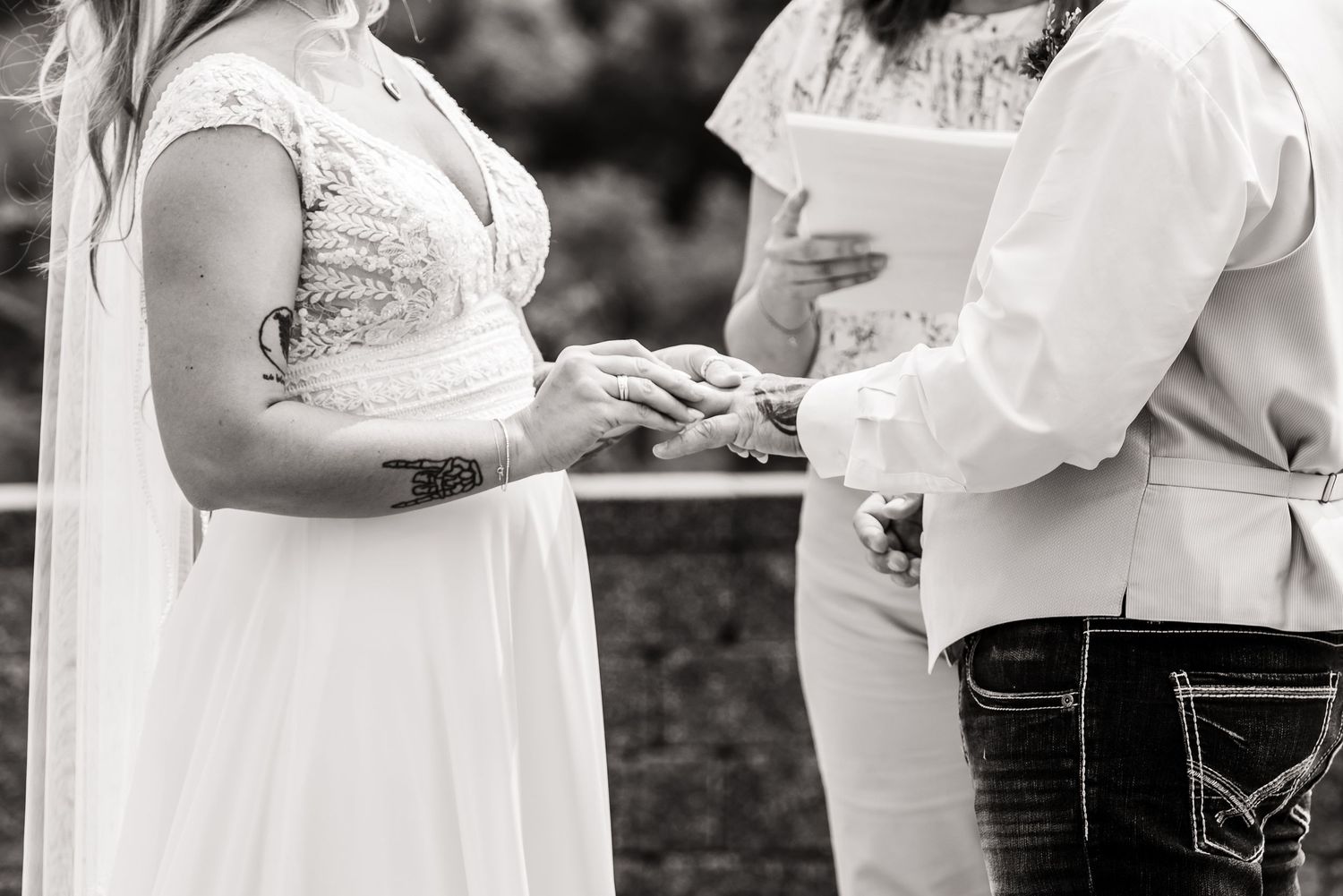 Black and white close-up of wedding ring exchange during ceremony.