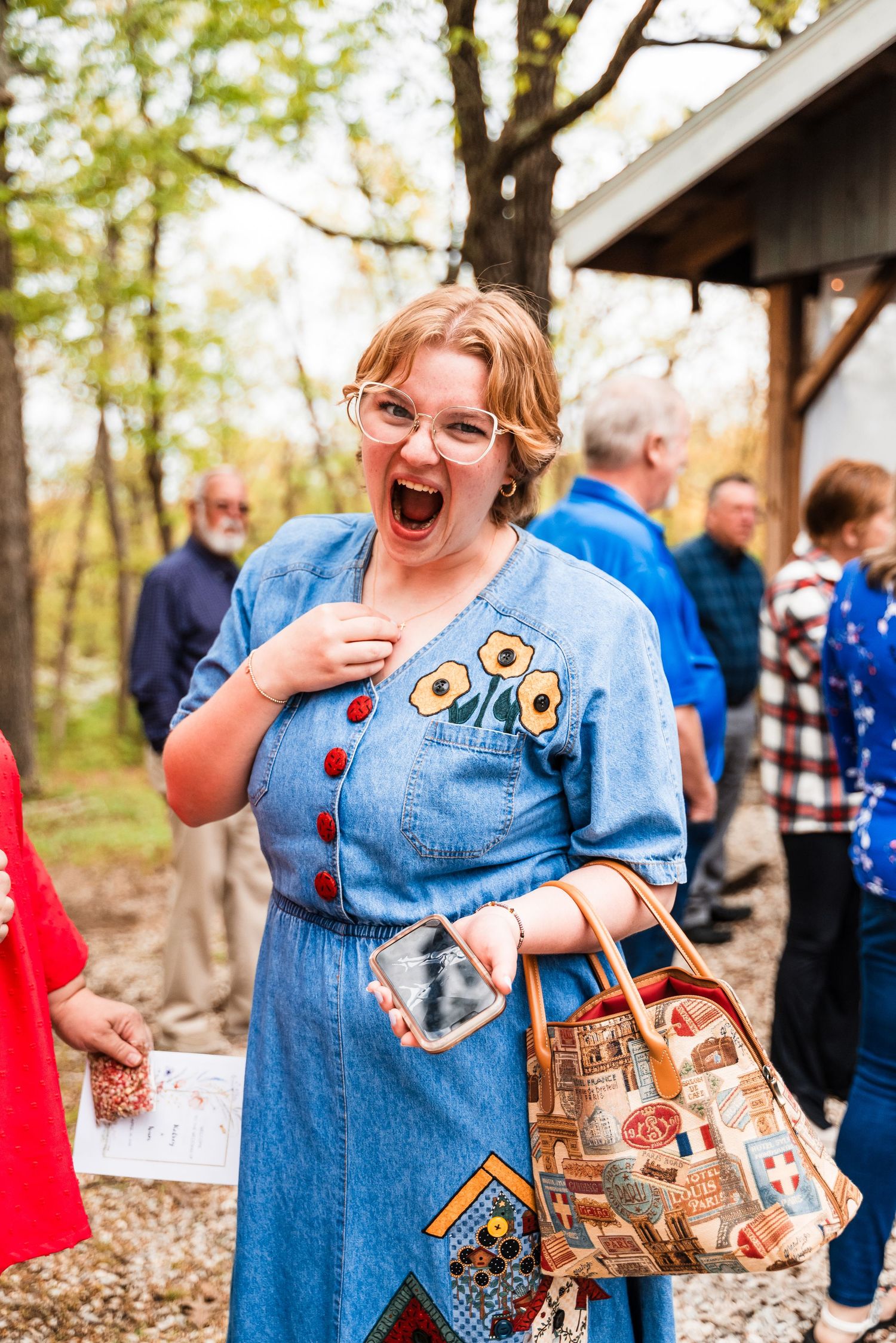 Woman in vintage-style denim dress shows excitement at outdoor gathering.