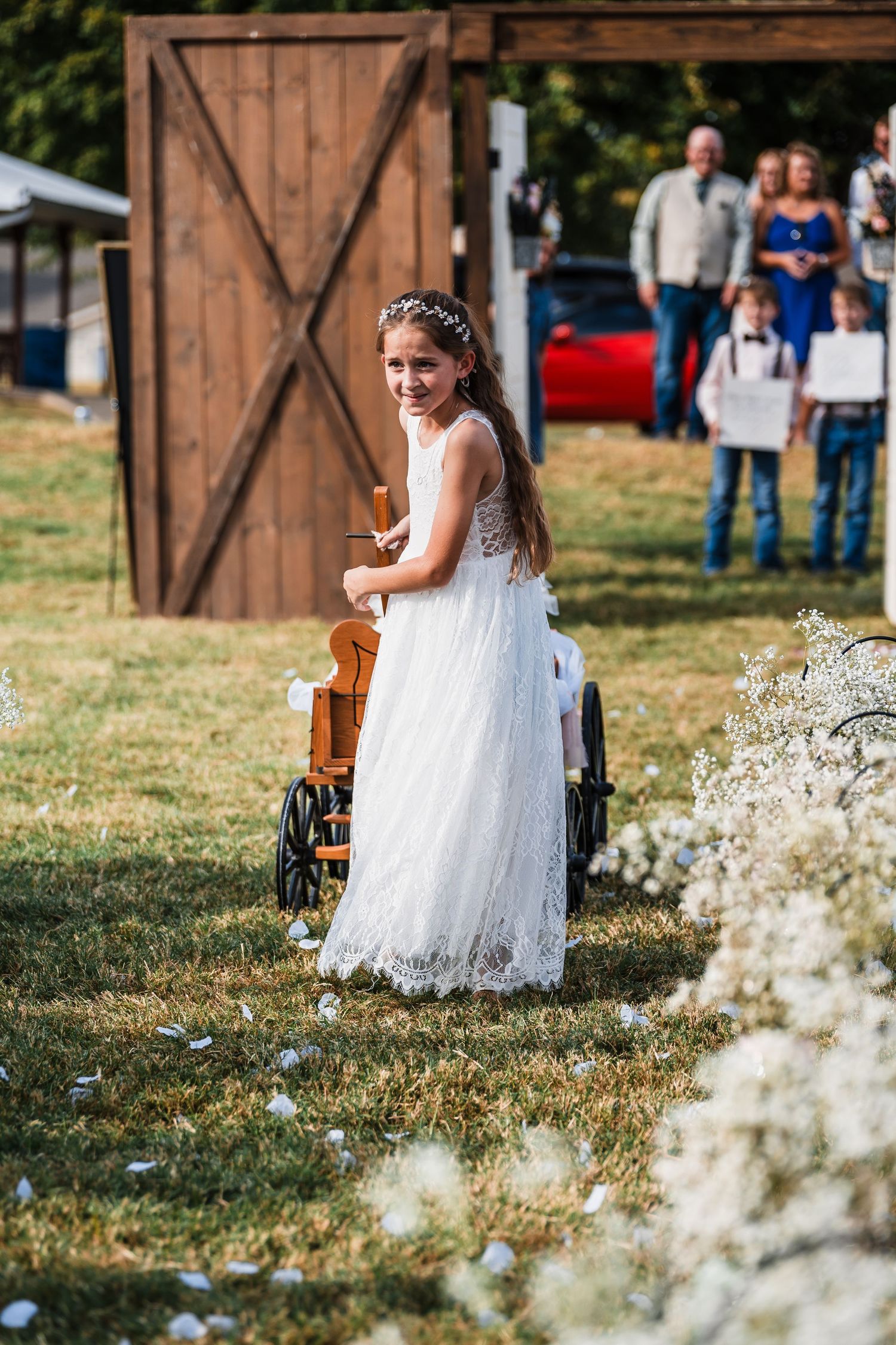 White lace dress flows in outdoor rustic wedding setting with wooden barn backdrop.