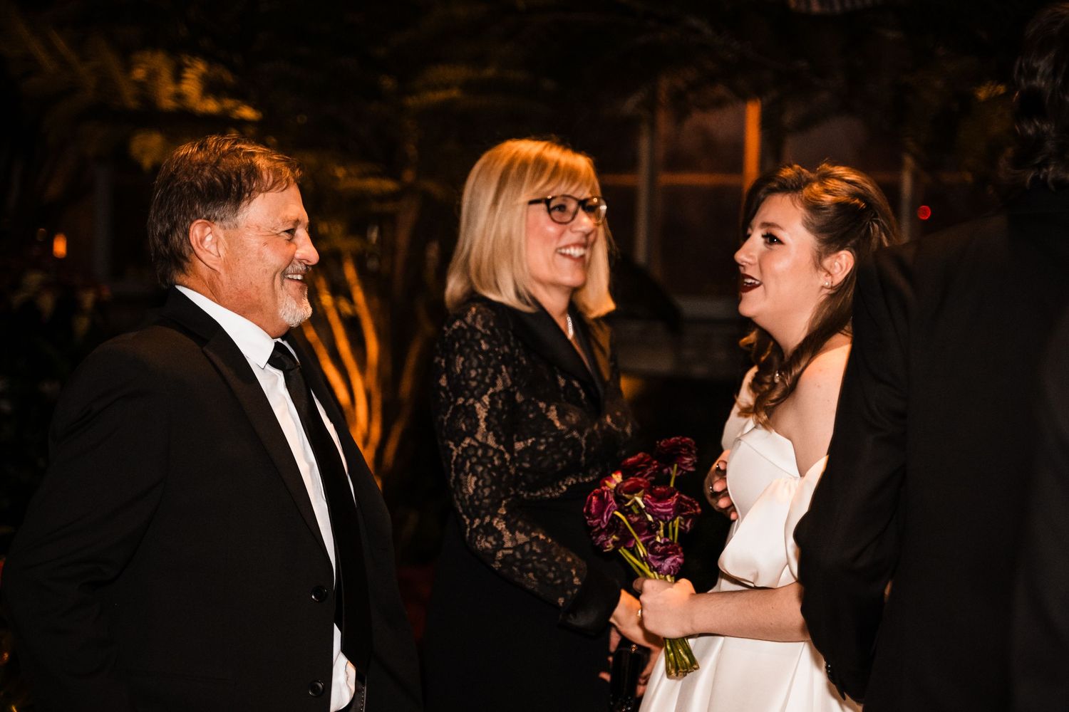 Wedding ceremony participants share a candid moment during an evening celebration.