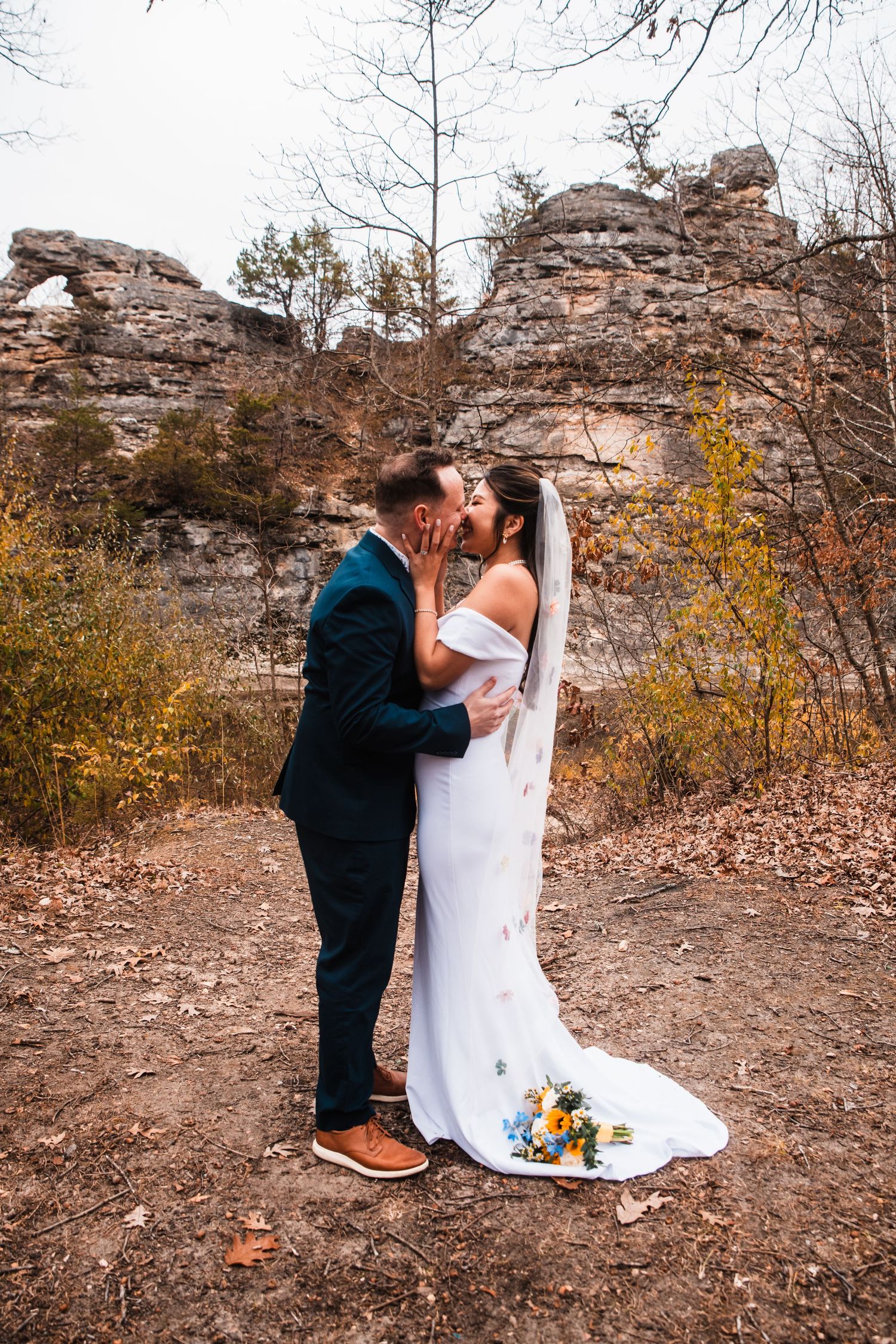 A tender wedding moment captured in front of dramatic rock formations and fall foliage.