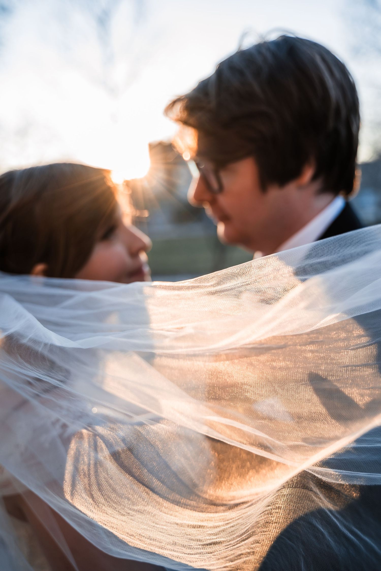 Romantic sunset portrait with flowing veil creating ethereal atmosphere.