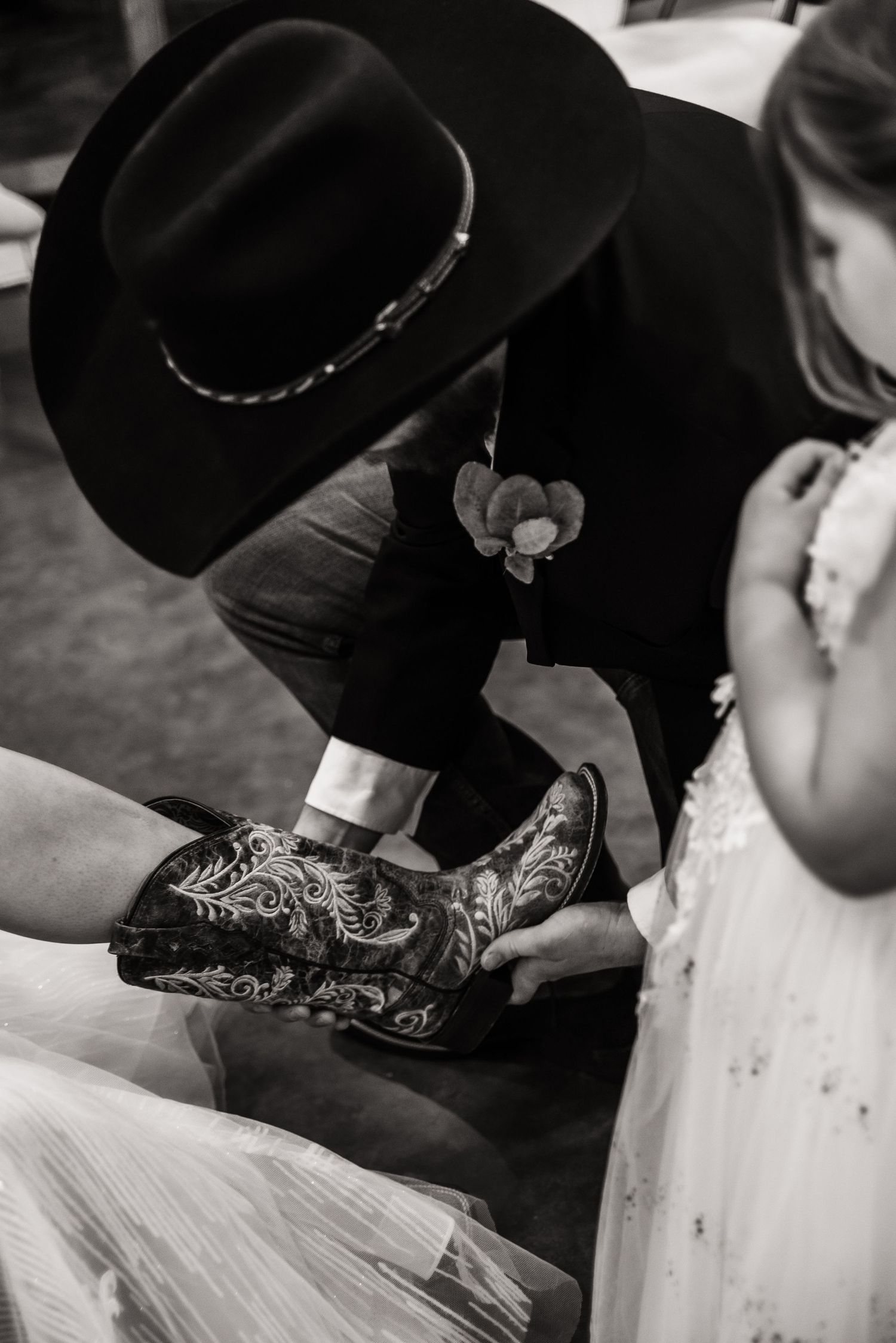 Close-up of ornate cowboy boot being adjusted at what appears to be a formal Western event.
