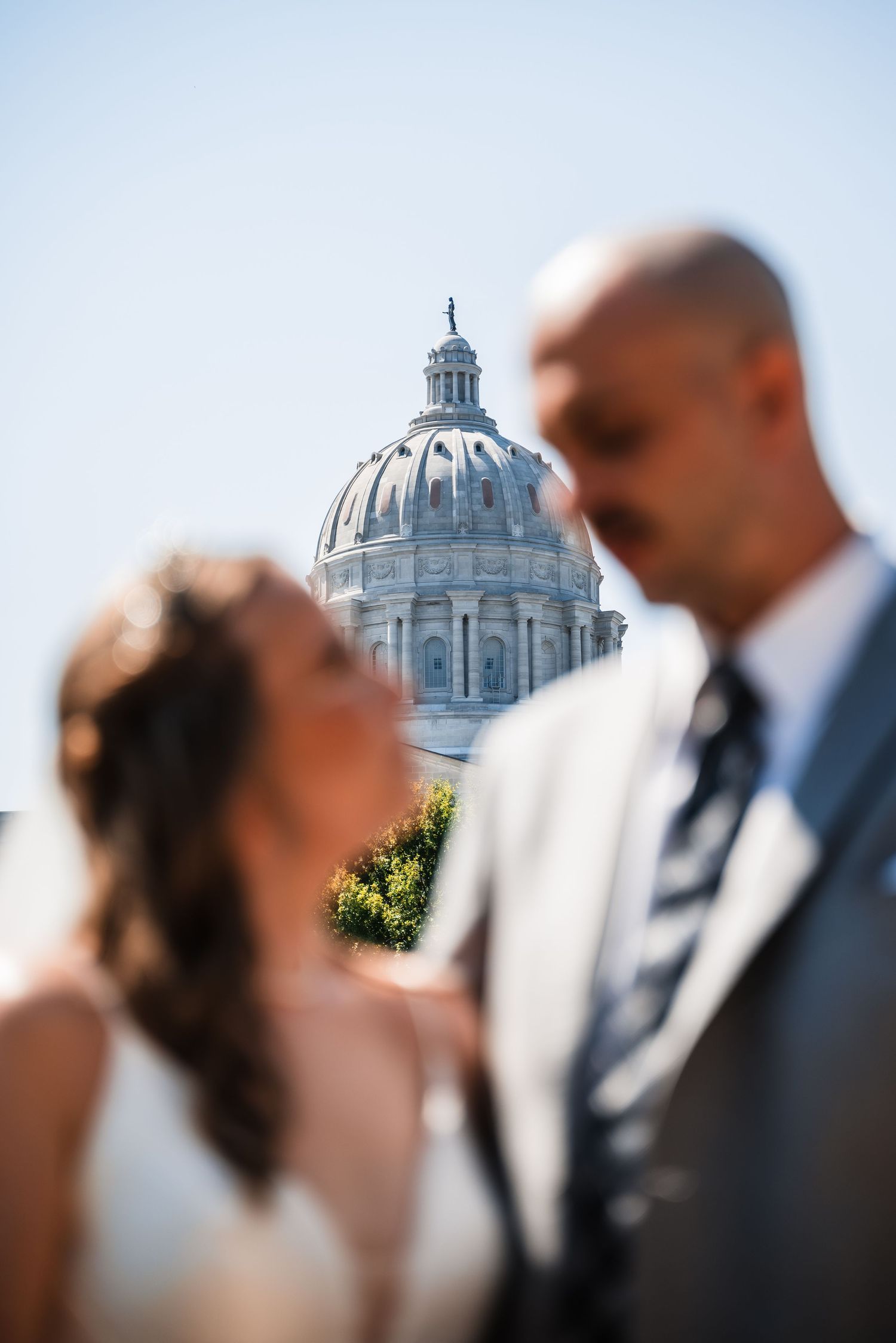 Artistic wedding photo with a domed capitol building in soft focus background.