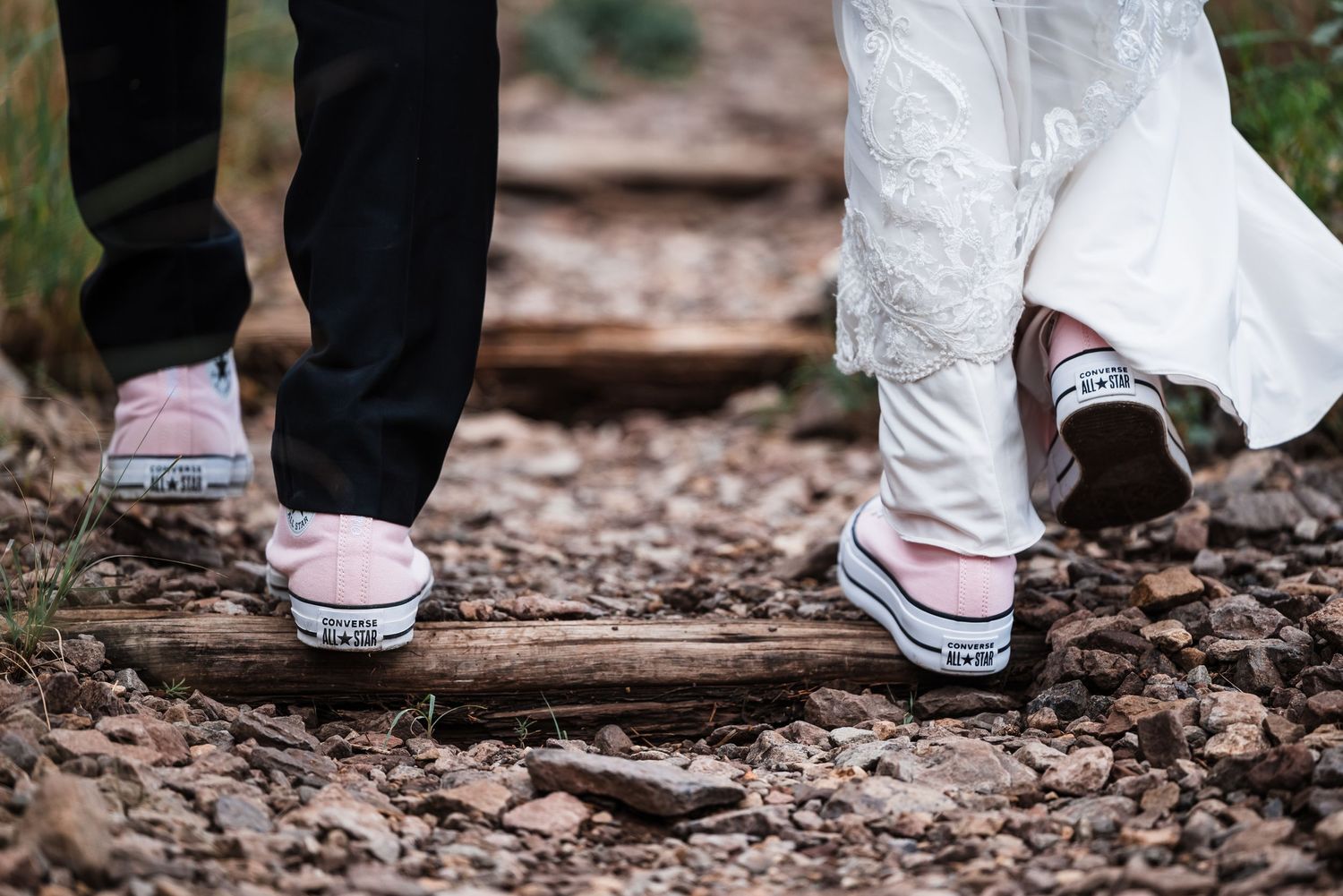 Close-up of two pairs of Converse sneakers worn by couple on woodland path.