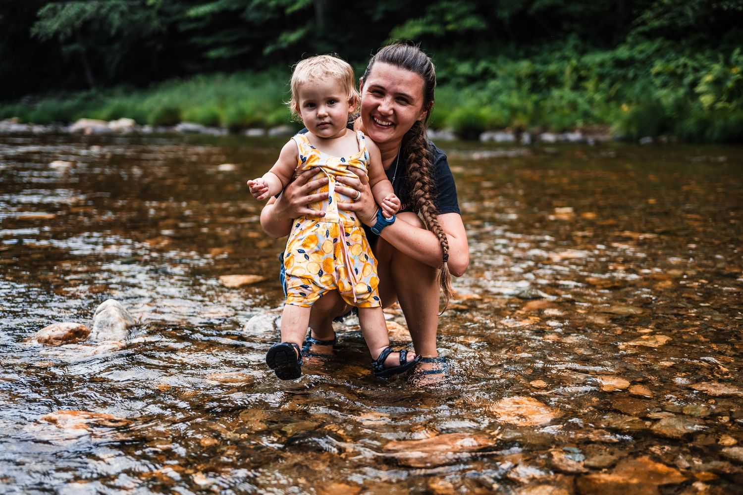 Two people enjoying a playful moment while standing in a shallow stream surrounded by nature.