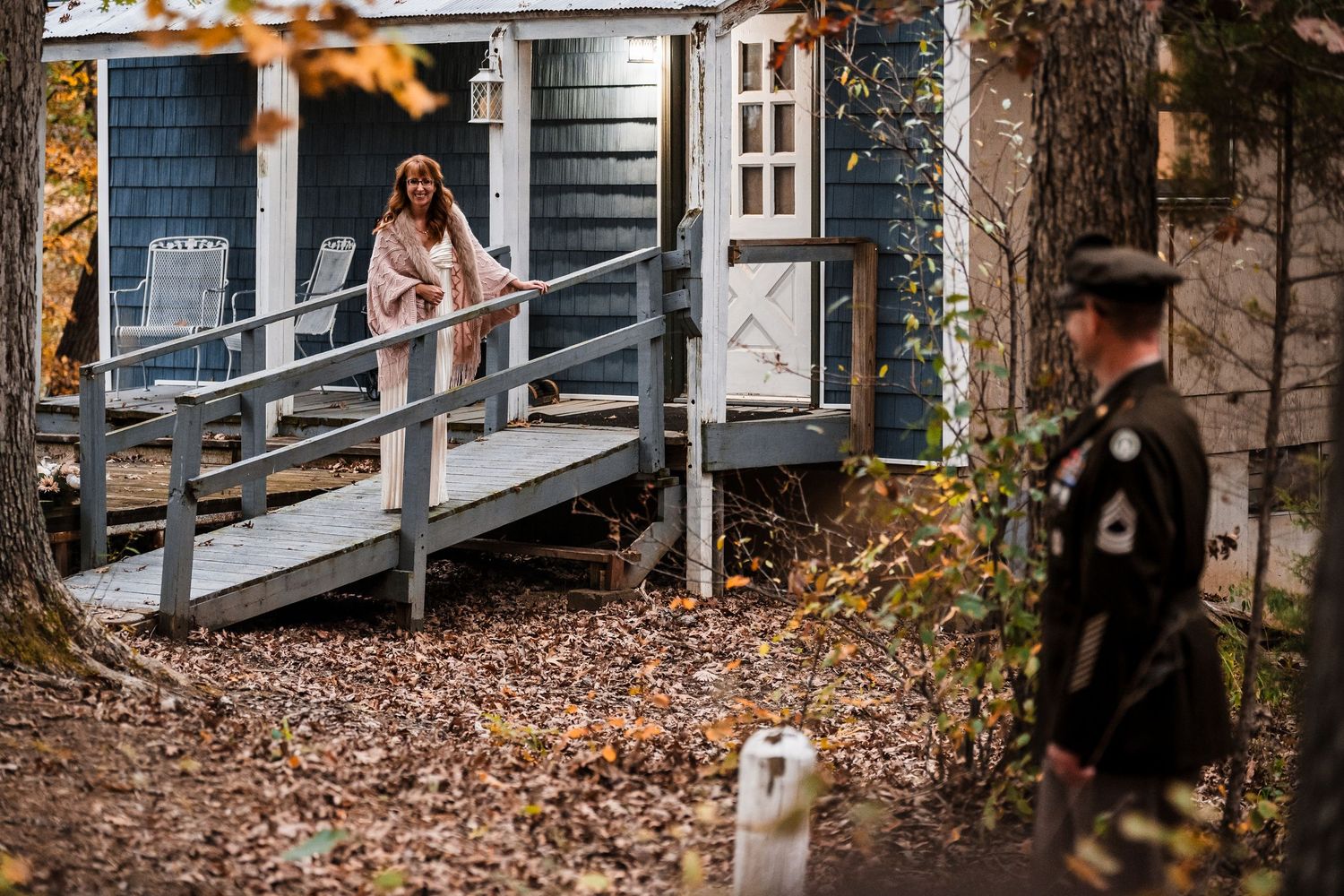 A cozy autumn scene with rustic wooden buildings surrounded by fallen orange leaves and natural woodland decor.