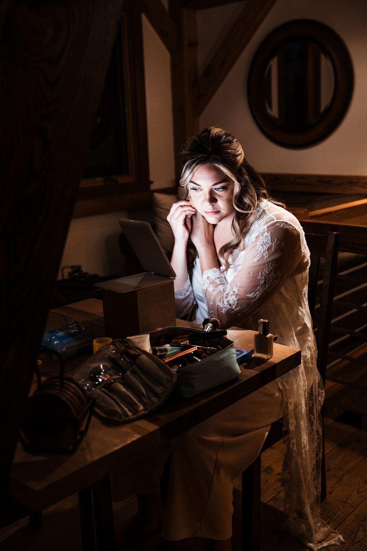 A series of moody boudoir photos showing a person in white lace in dark lighting at a desk.