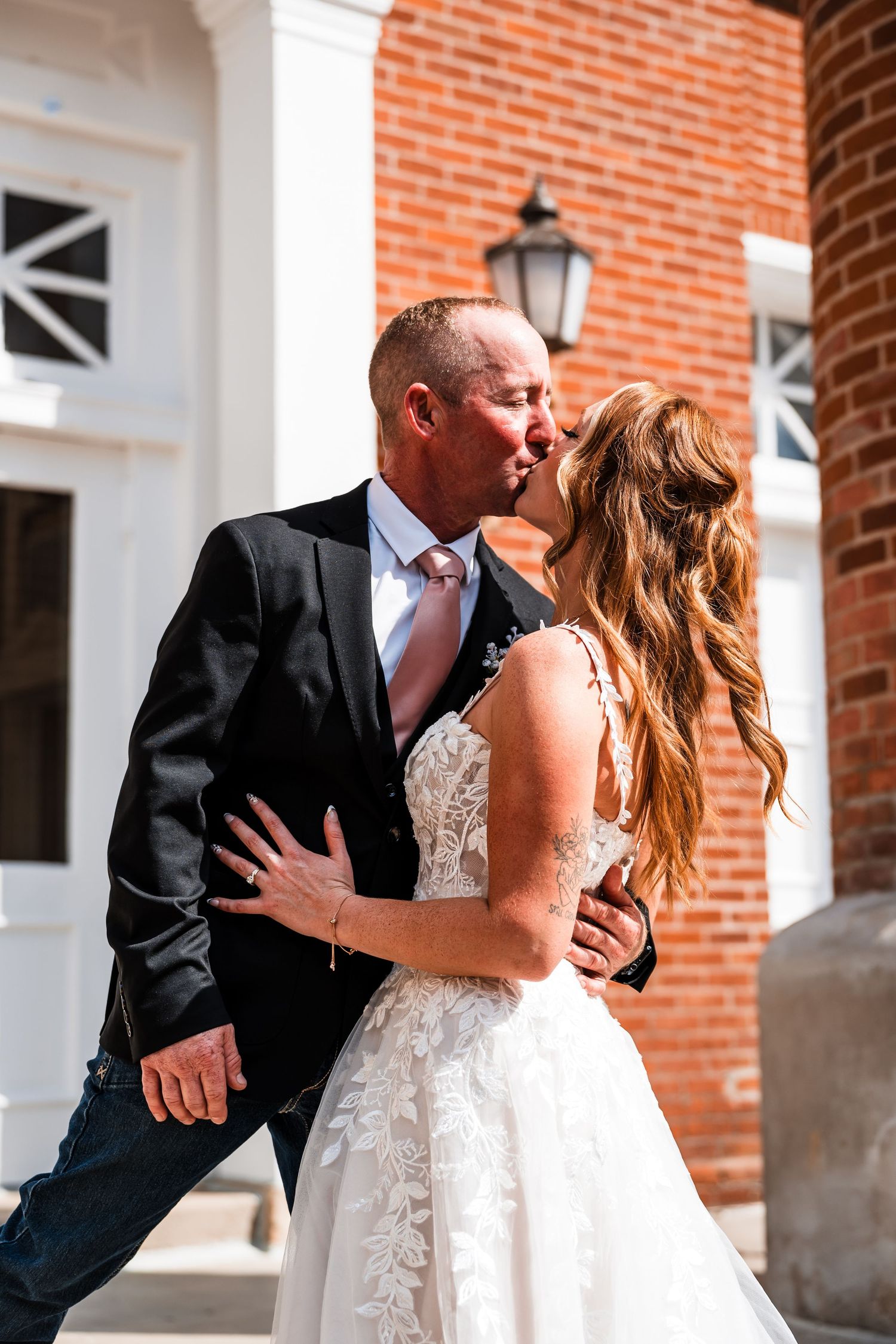 A romantic first look moment unfolds against a brick building backdrop.