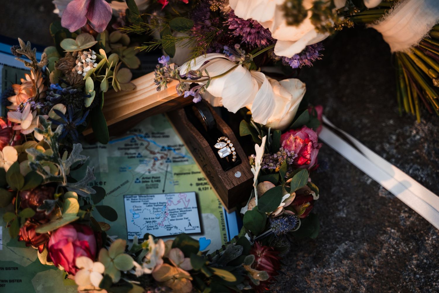 Handwritten vows and dried flower petals arranged on dark surface.