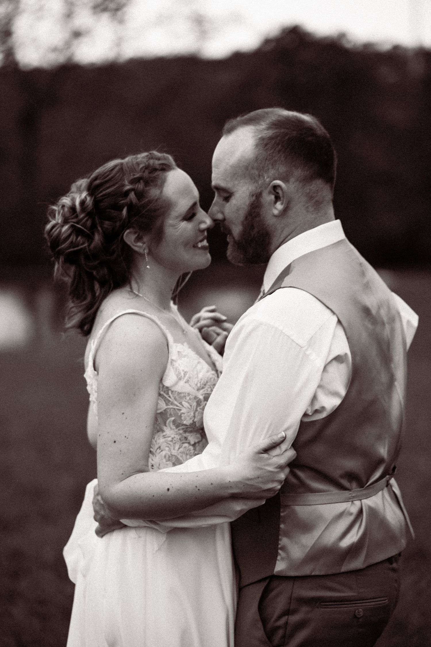 Black and white portrait of bride and groom sharing a tender moment outdoors.