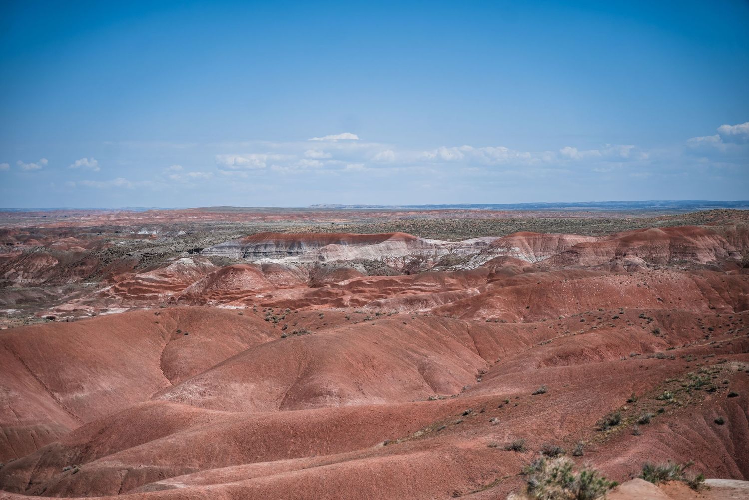 Scenic view of red rock formations and desert landscape under blue sky.