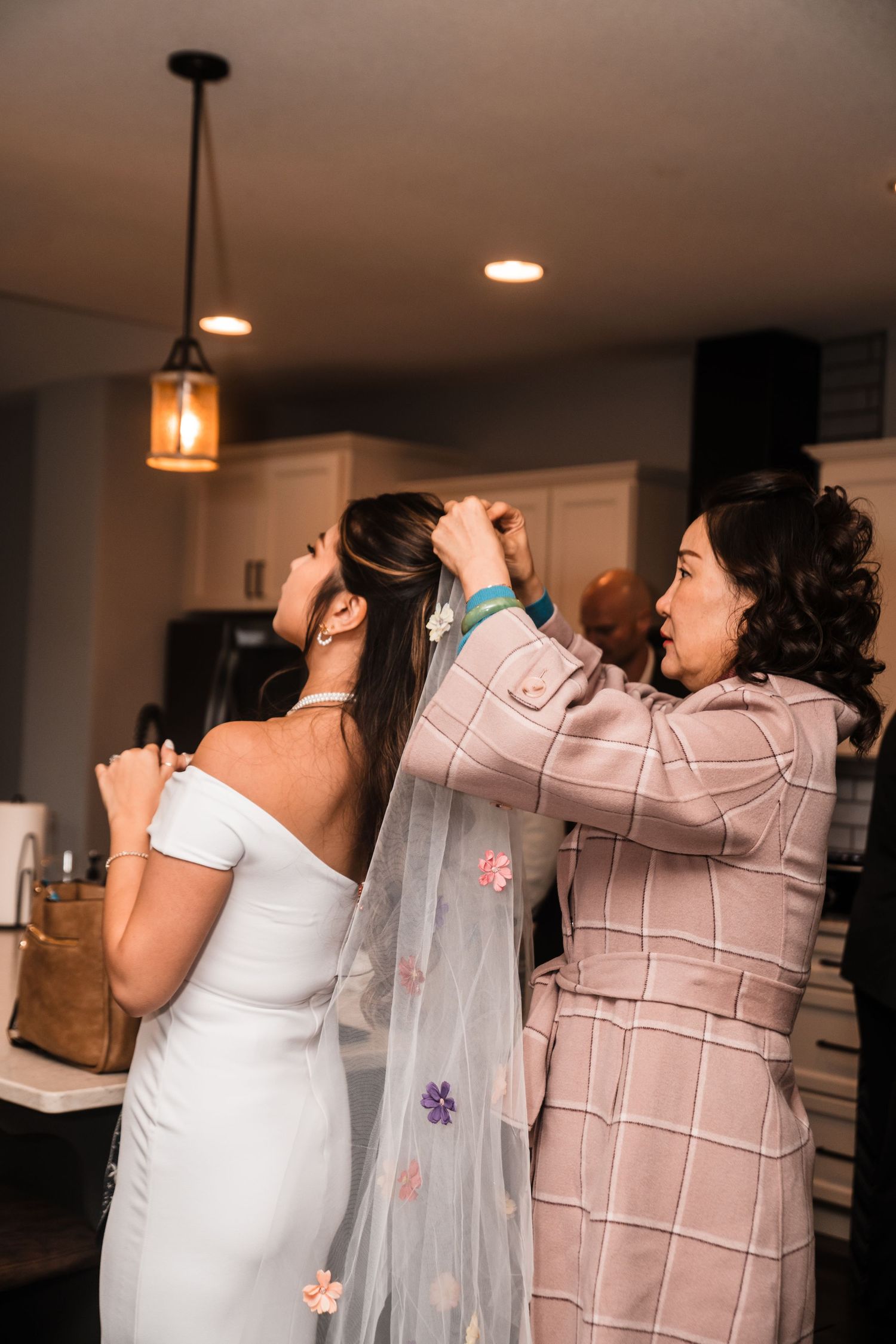 A wedding veil being adjusted in an indoor setting with warm lighting and modern decor.