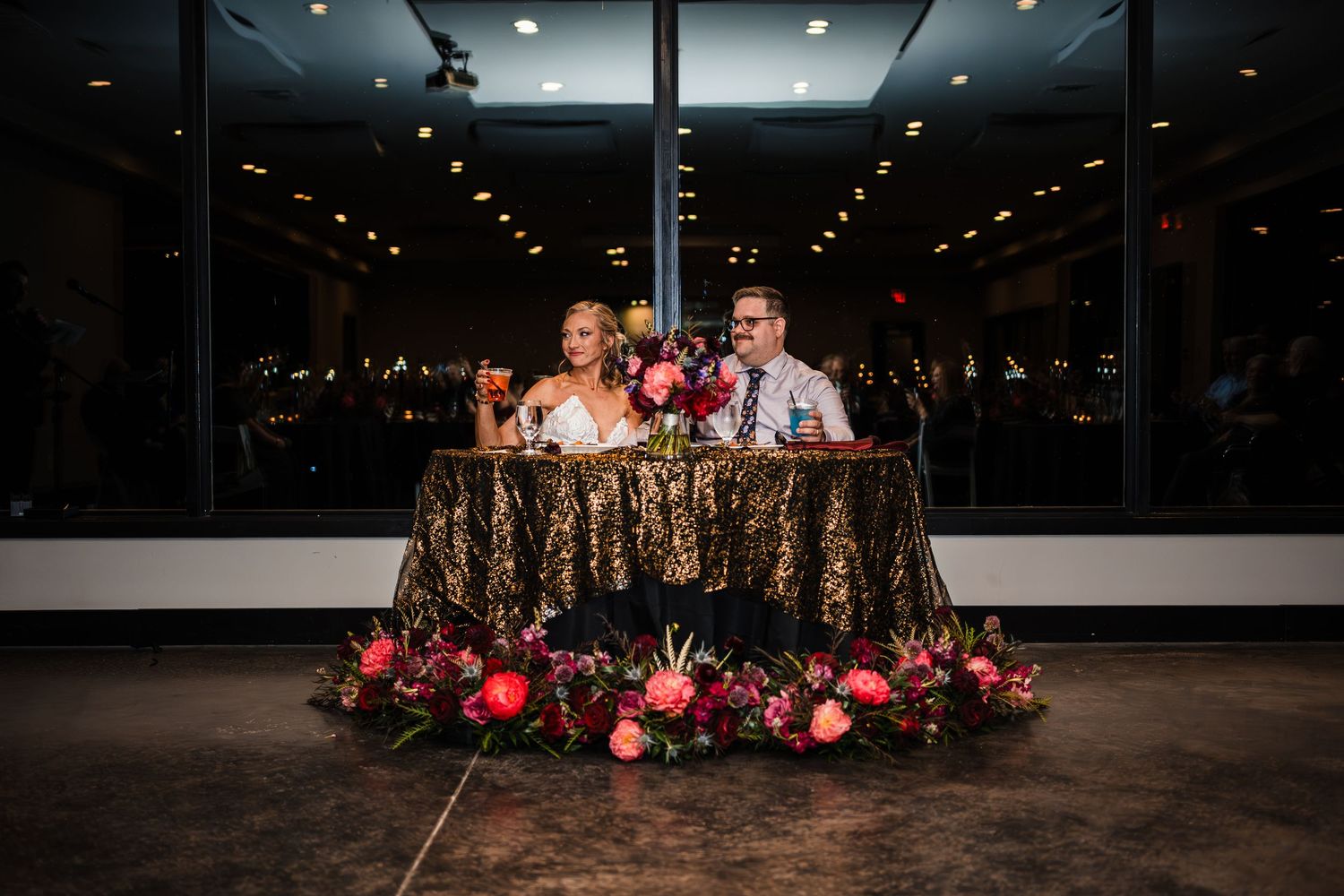 Modern wedding reception venue with dramatic lighting and floral decorations.