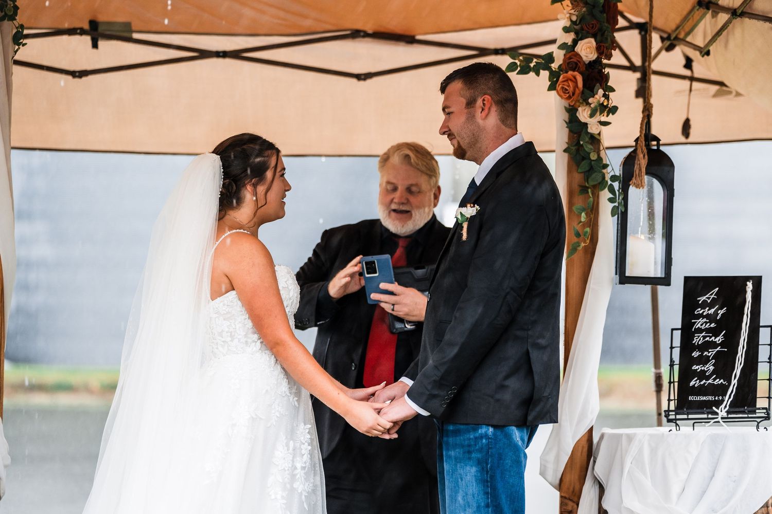 Wedding reception setup under white tent with guests mingling.