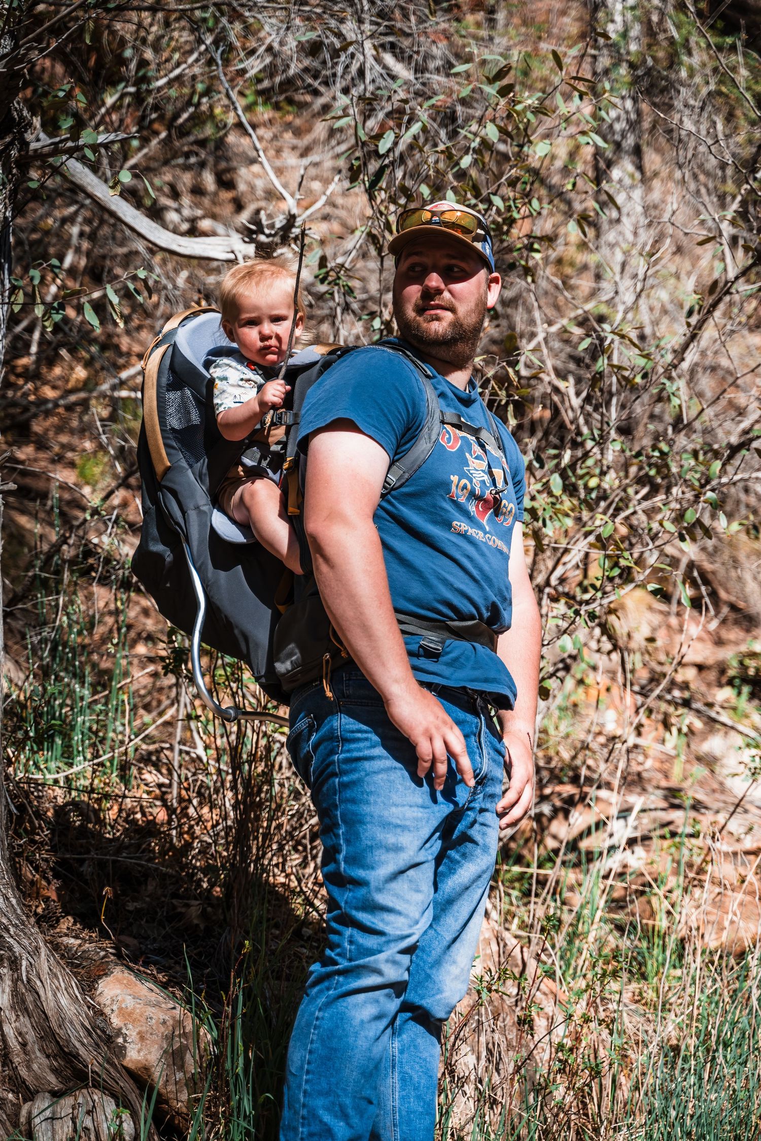 Parent carrying child in hiking backpack carrier while exploring outdoor trail.