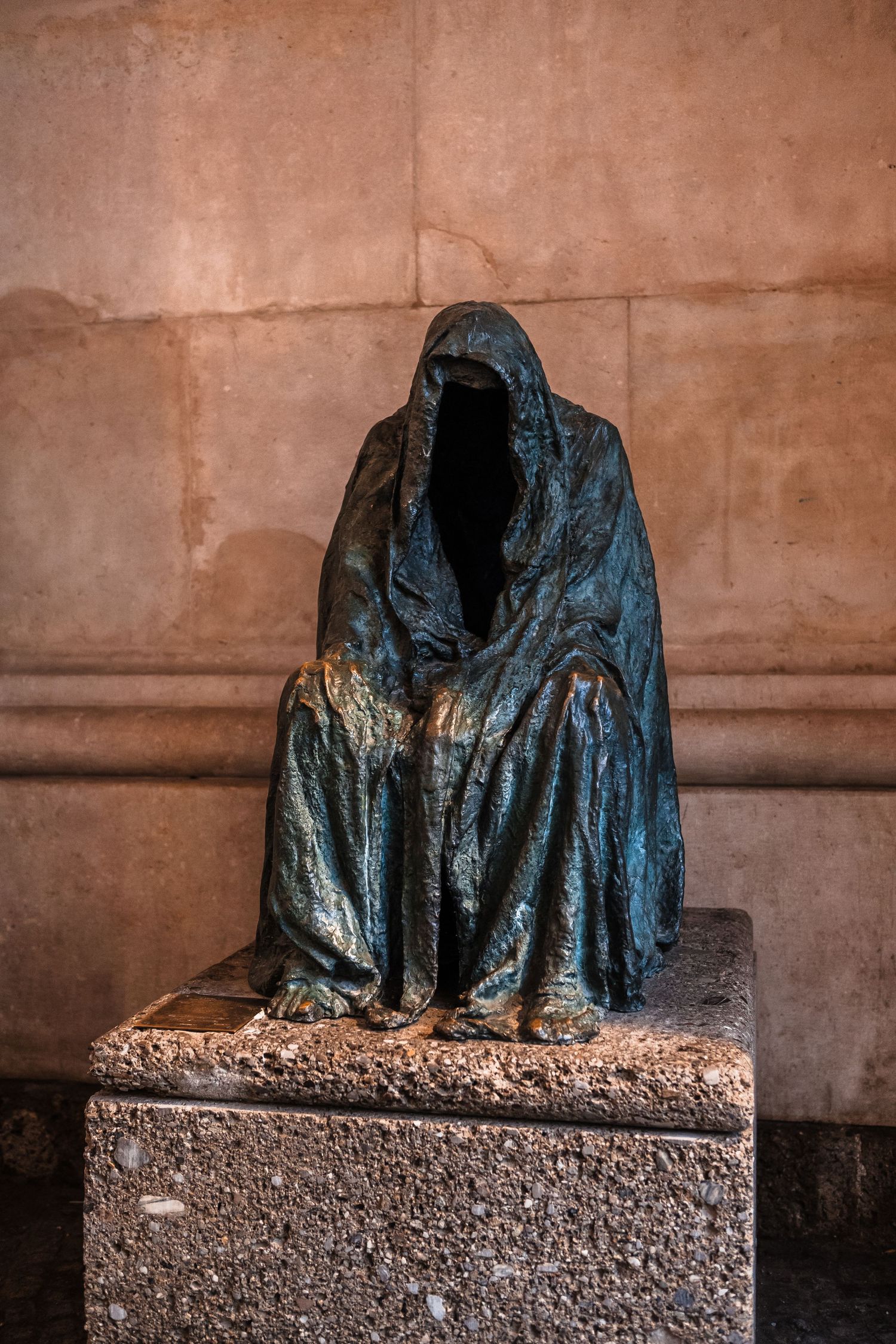 Haunting bronze sculpture of a hooded figure with empty dark void where face should be.