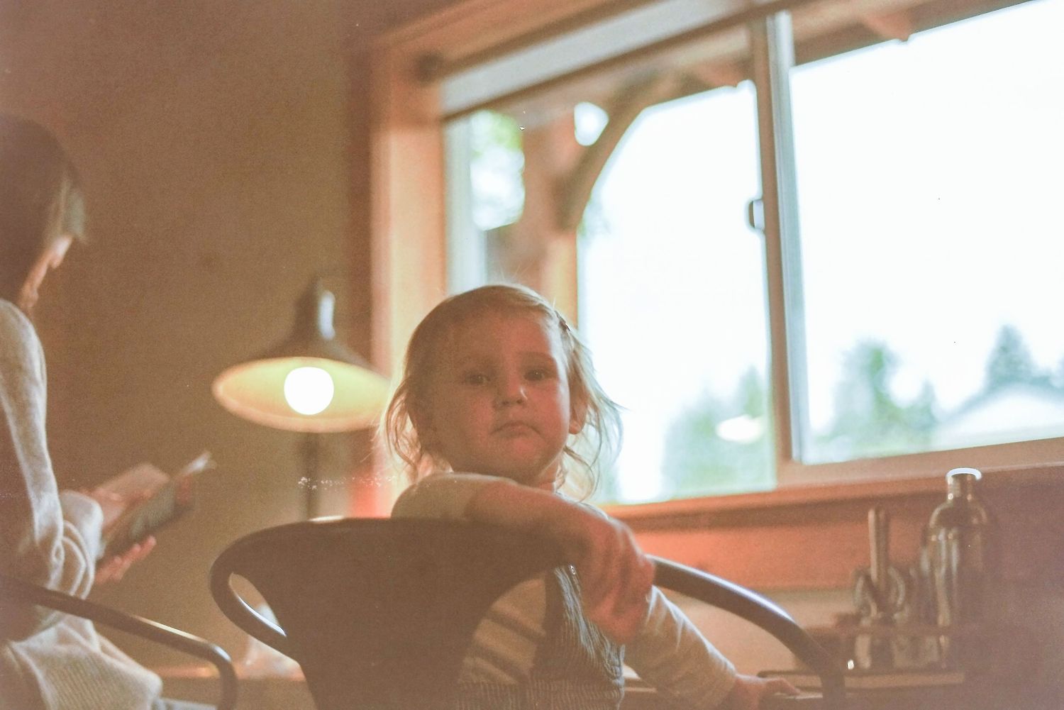 Sunlit interior scene with someone sitting at a steering wheel, bathed in warm golden light through a window.