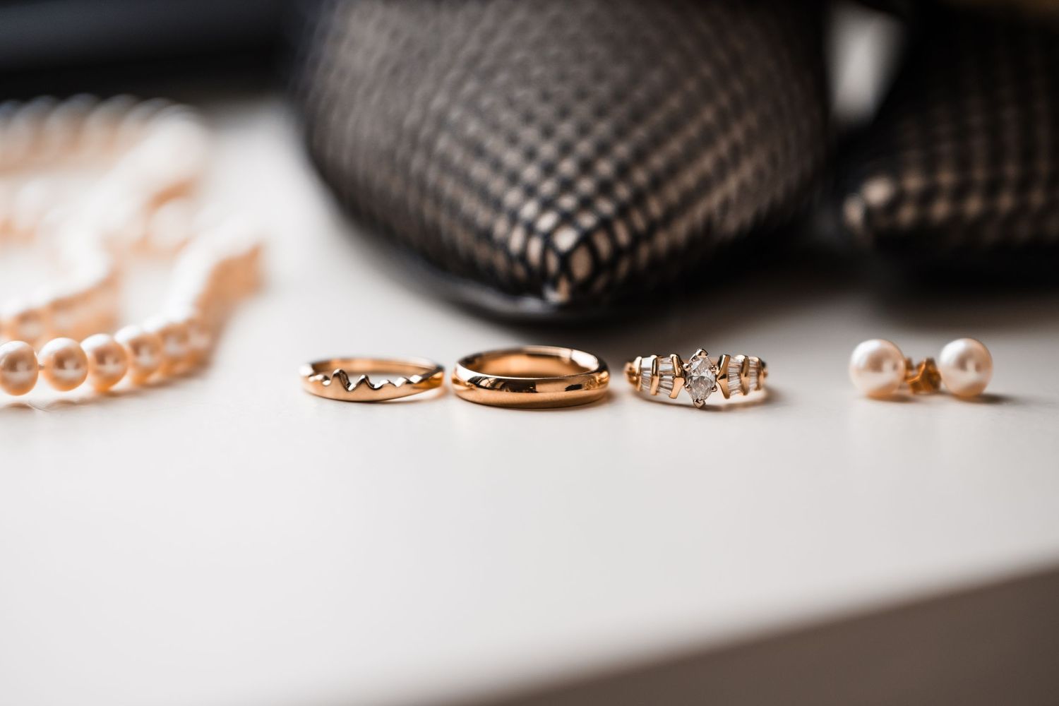 Gold wedding rings and jewelry pieces arranged on white surface with selective focus.