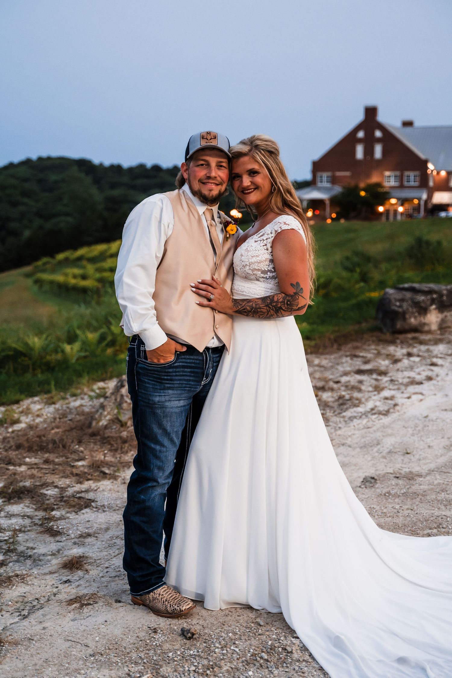 Wedding couple poses for romantic beachside photos at sunset with rustic house in background.