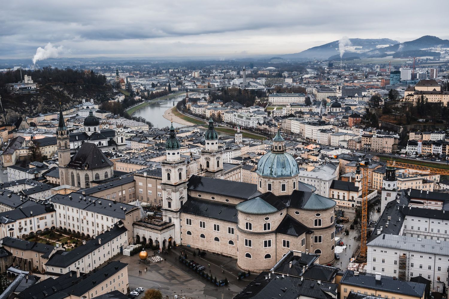 Panoramic aerial view of a historic European city with traditional architecture and church spires against cloudy skies.