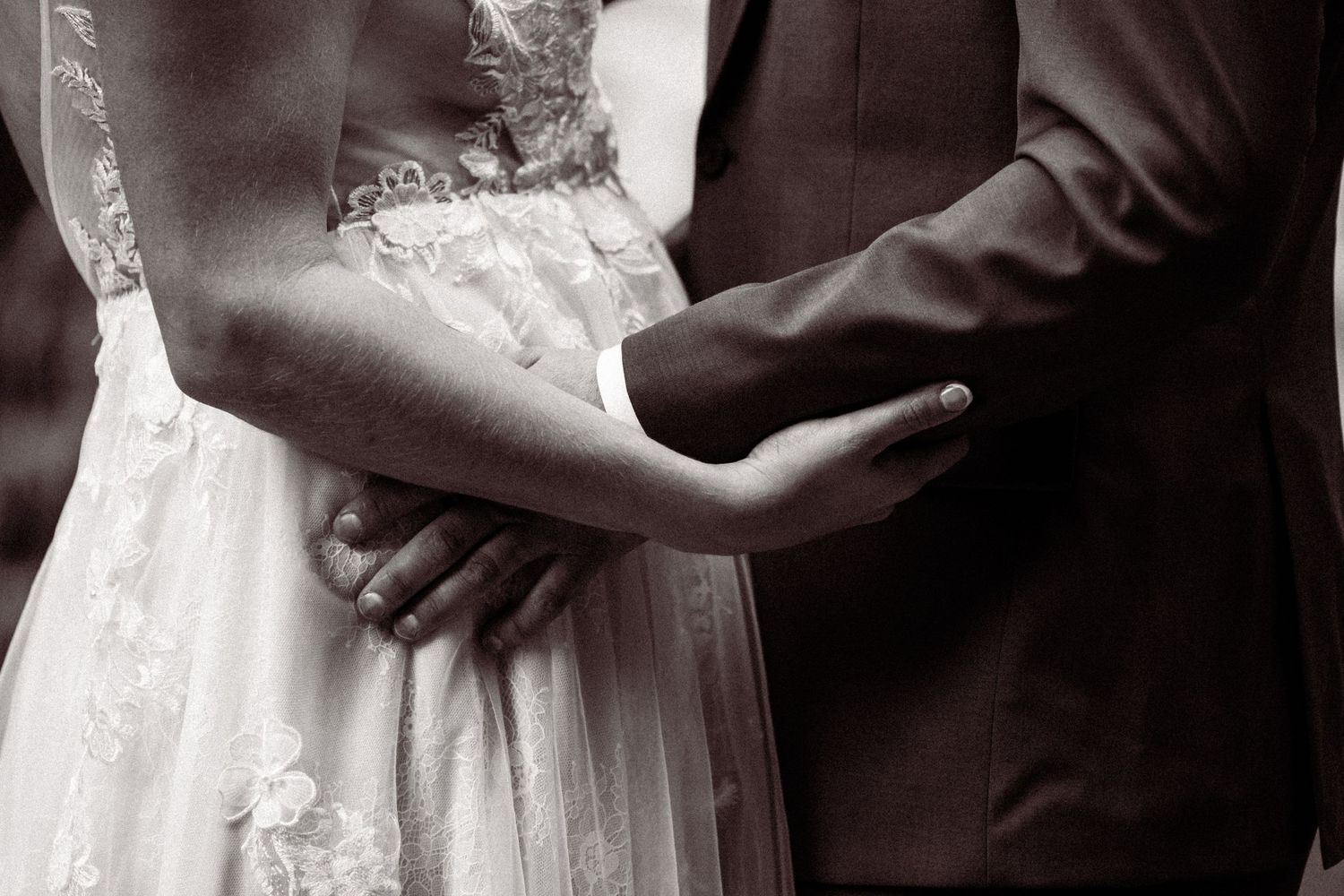 Close-up details of wedding attire showing delicate lace and fabric textures in black and white.