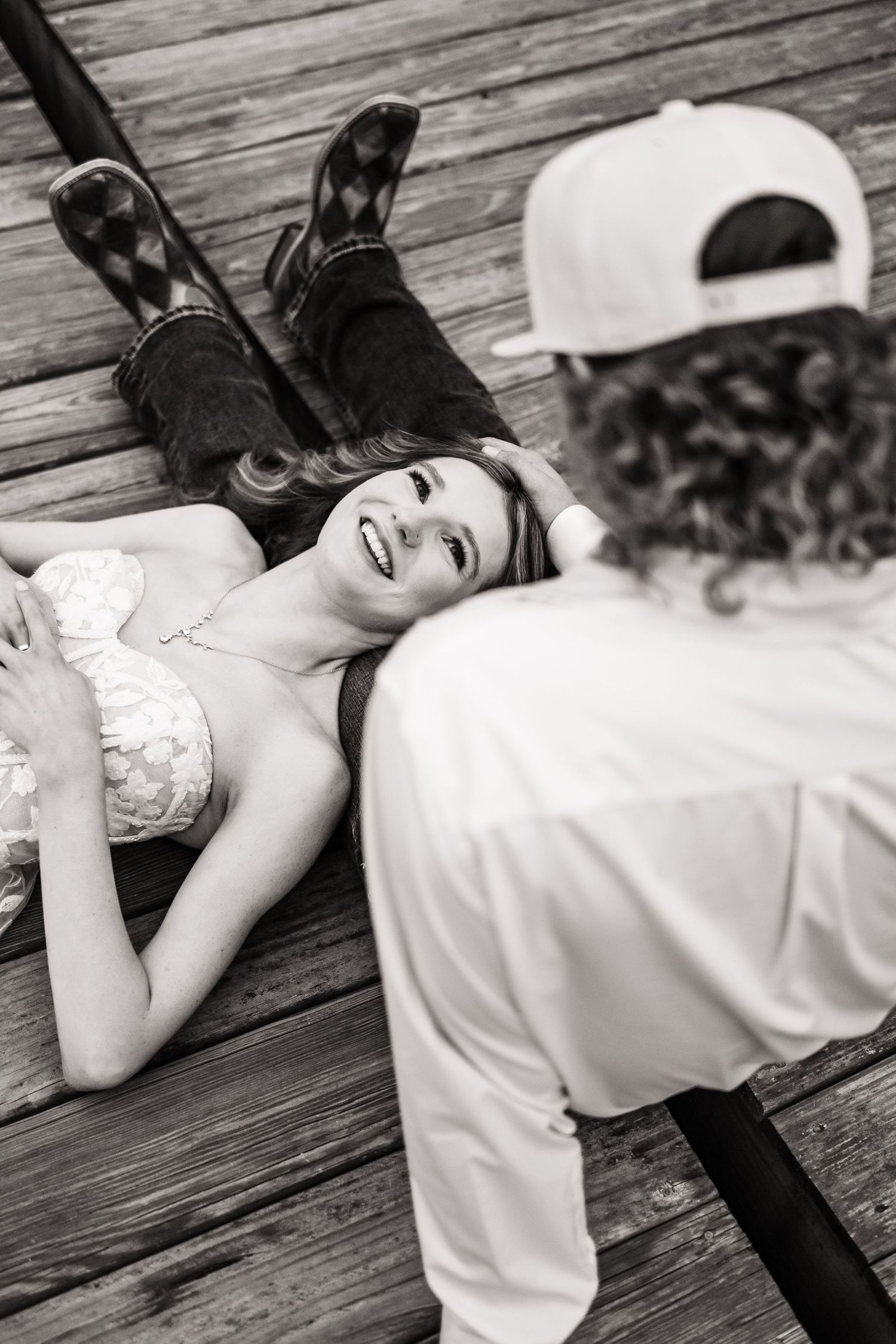 A candid black and white wedding photo captured on a rustic wooden deck.