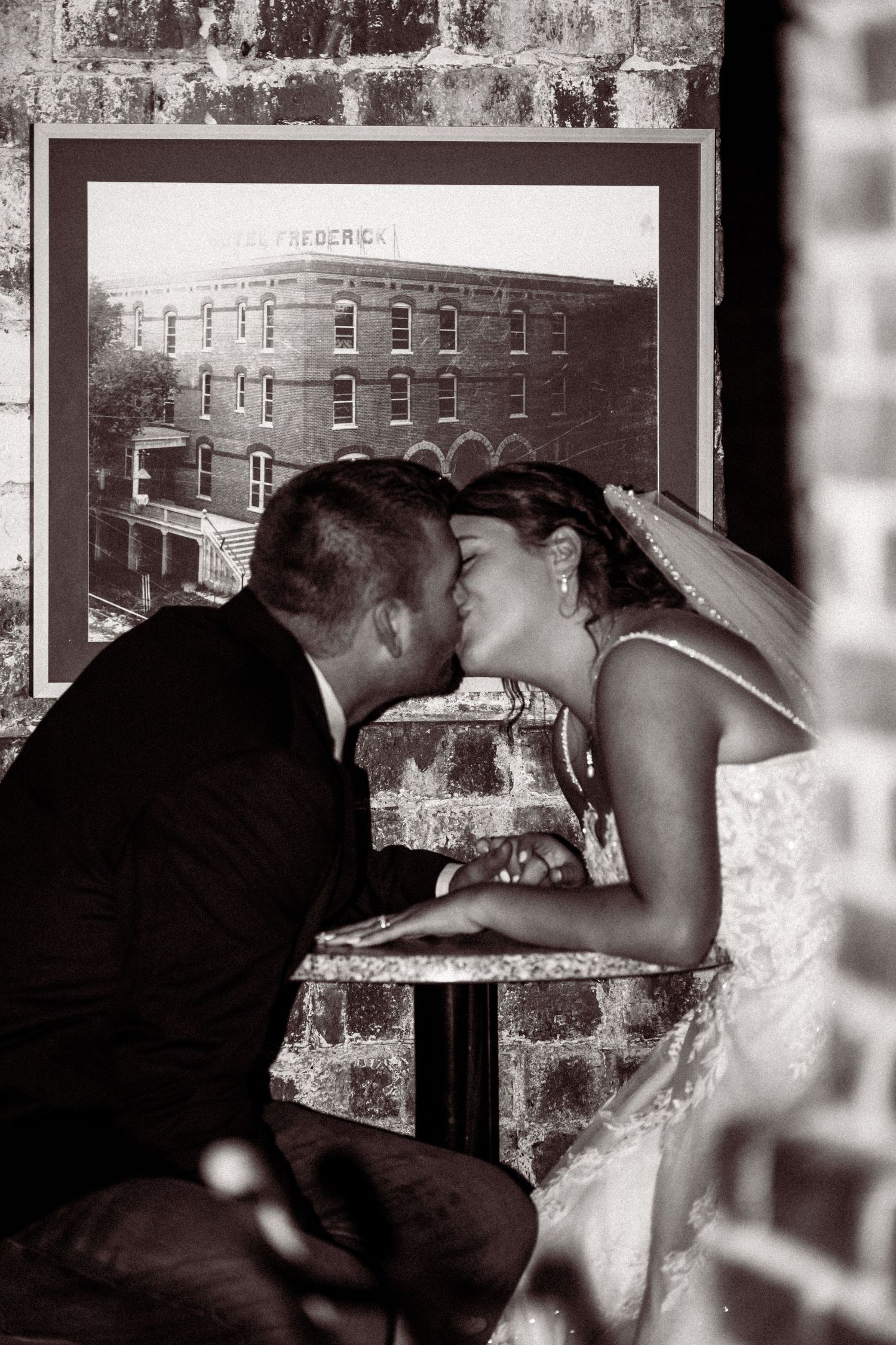 Black and white wedding photo series showing romantic kisses through window frames.