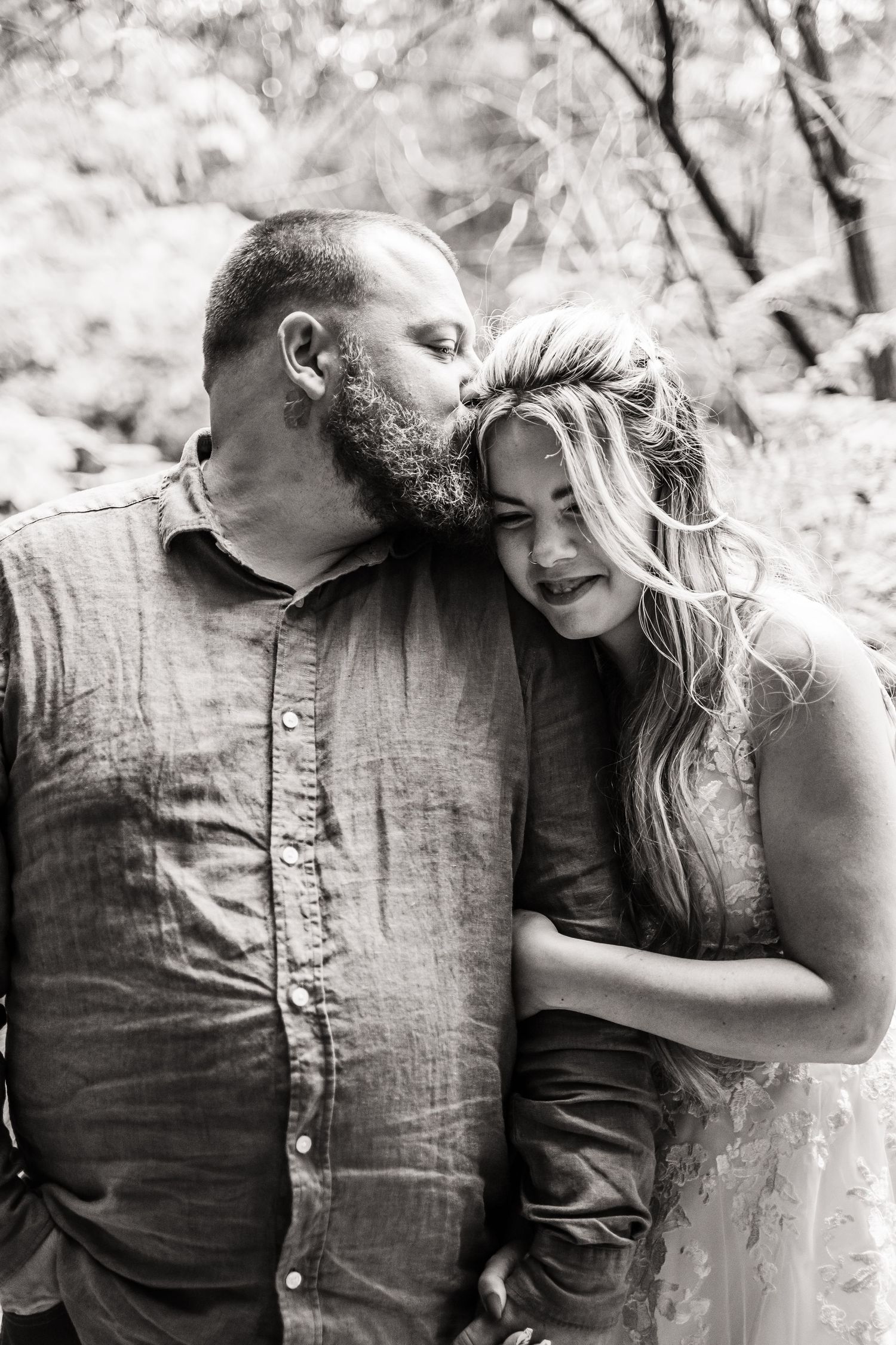 Intimate black and white portrait of a couple sharing a tender moment outdoors.