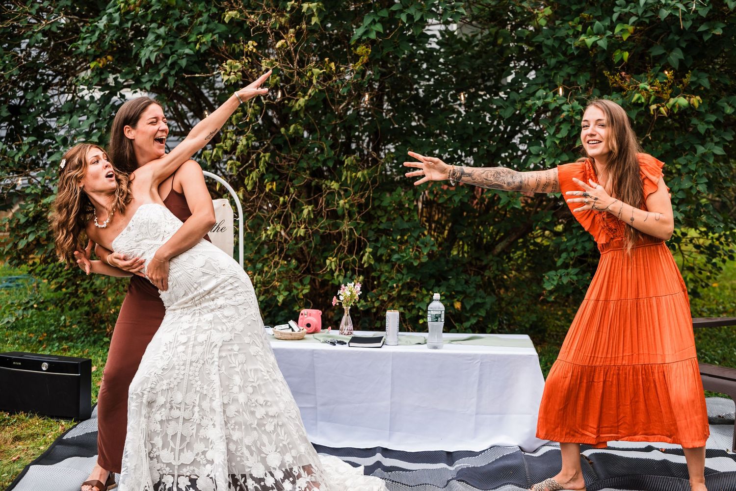 Wedding celebration with people dancing and having fun near a decorated table outdoors.