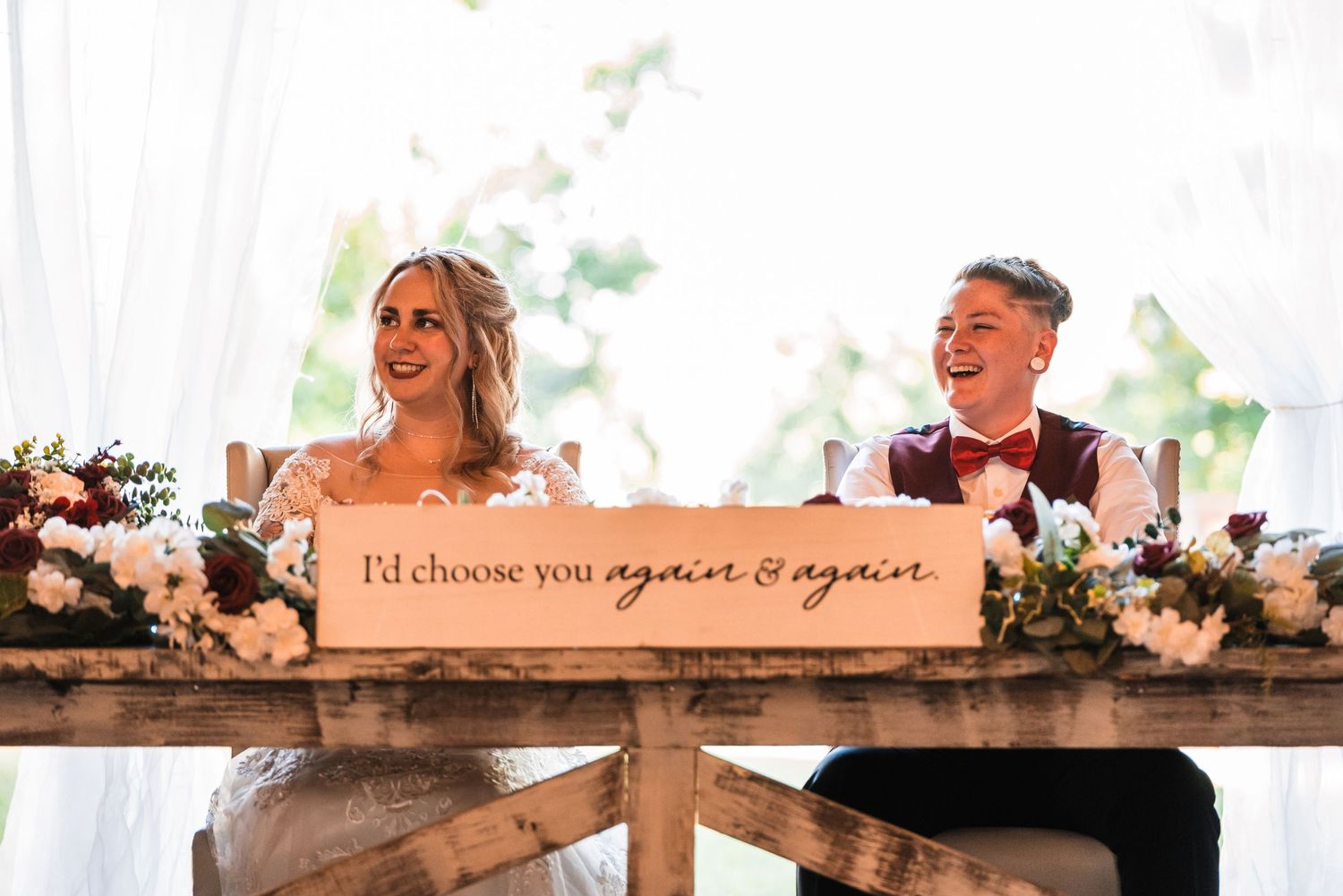 Wooden sign reading 'I'd choose you again & again' displayed at rustic wedding venue.
