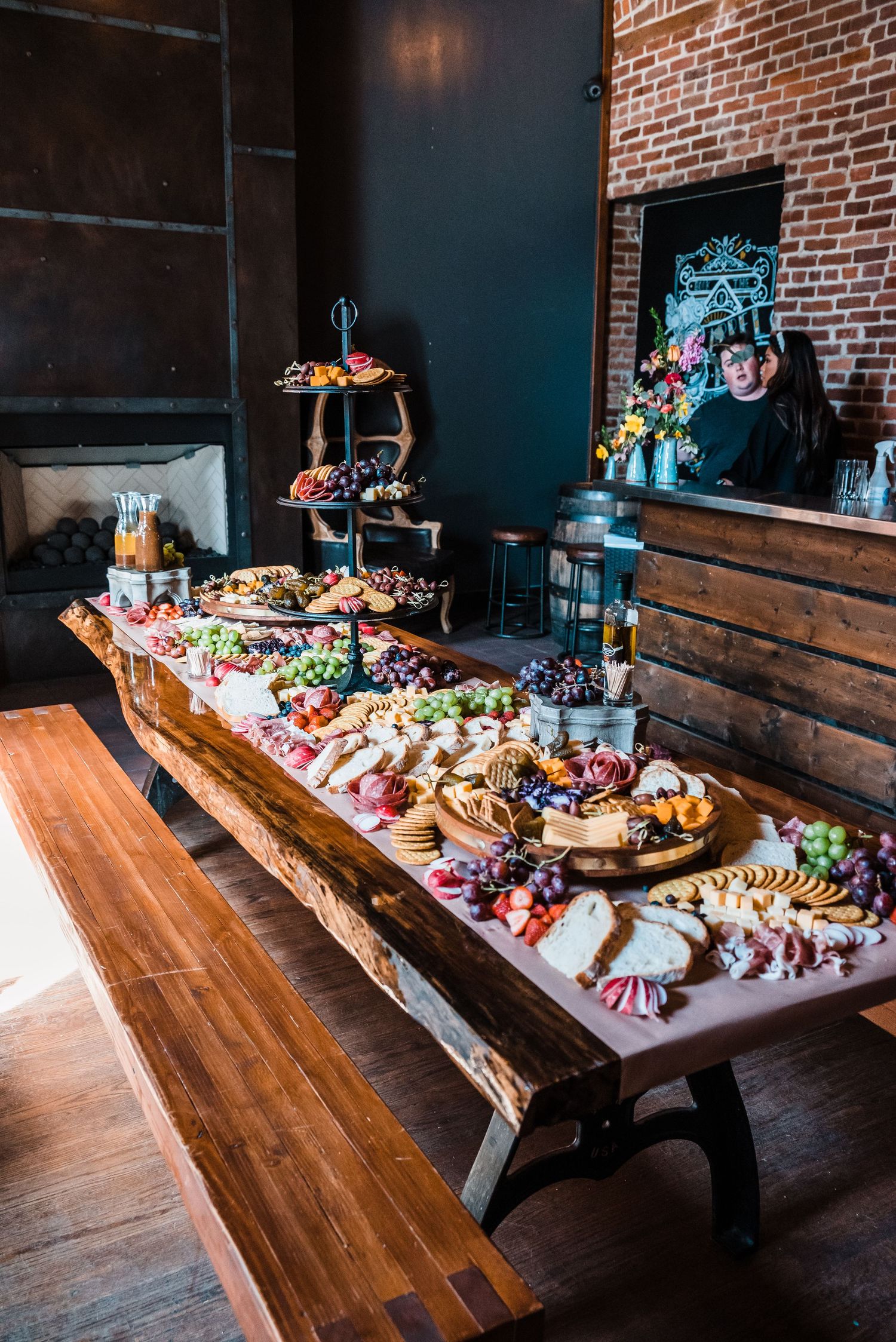 Long wooden table decorated with an elaborate charcuterie spread at a wedding reception.