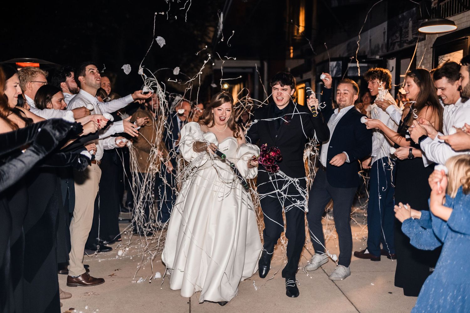 Wedding couple making their grand exit through a crowd of guests holding sparklers.