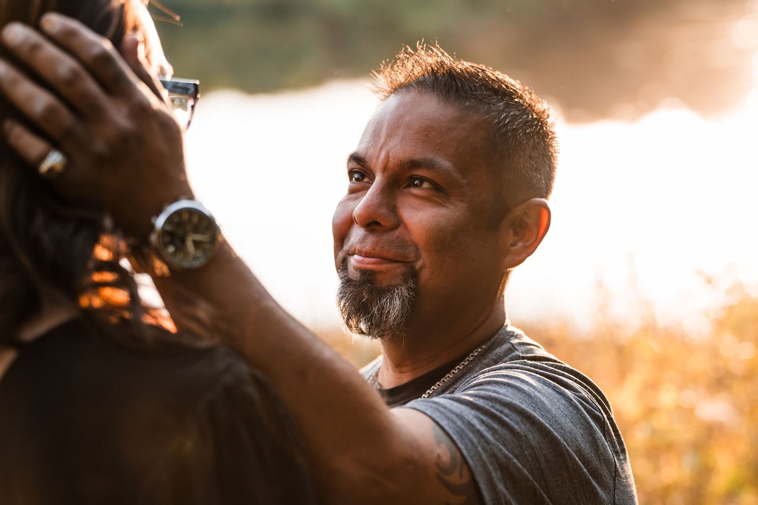 Person laughing and smiling while sitting outdoors during golden hour sunset lighting.