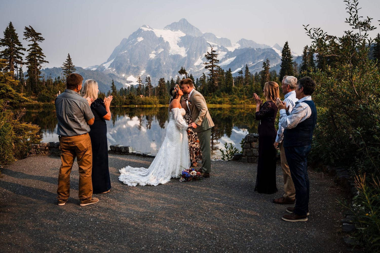 Wedding ceremony taking place in a scenic mountain landscape with snow-capped peaks and evergreen trees.