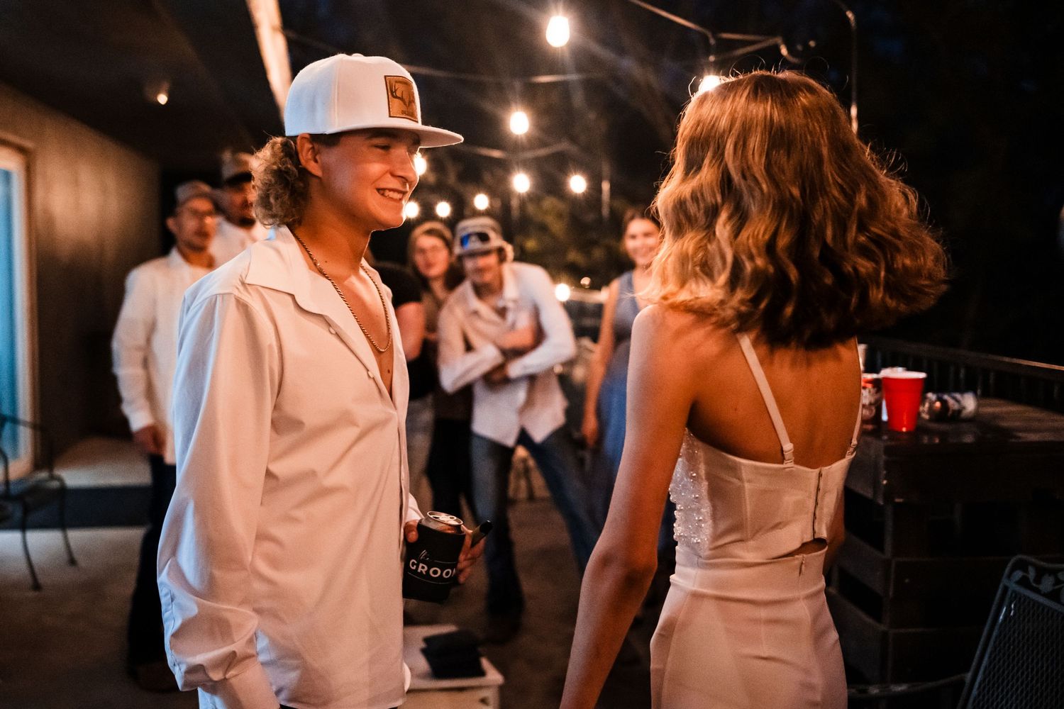 Couple in white having an intimate moment during wedding reception party.